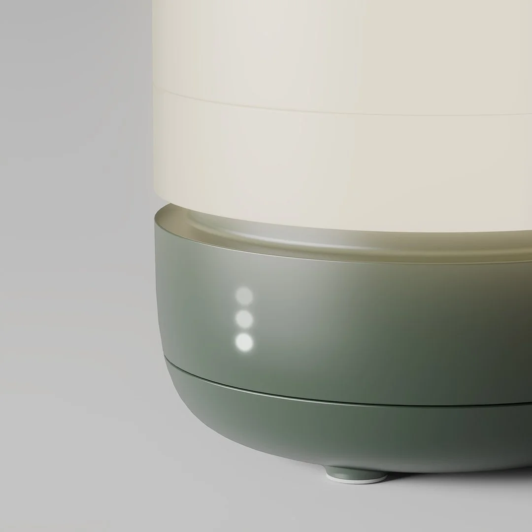 Close-up of a modern humidifier with three indicator lights on a light gray surface.