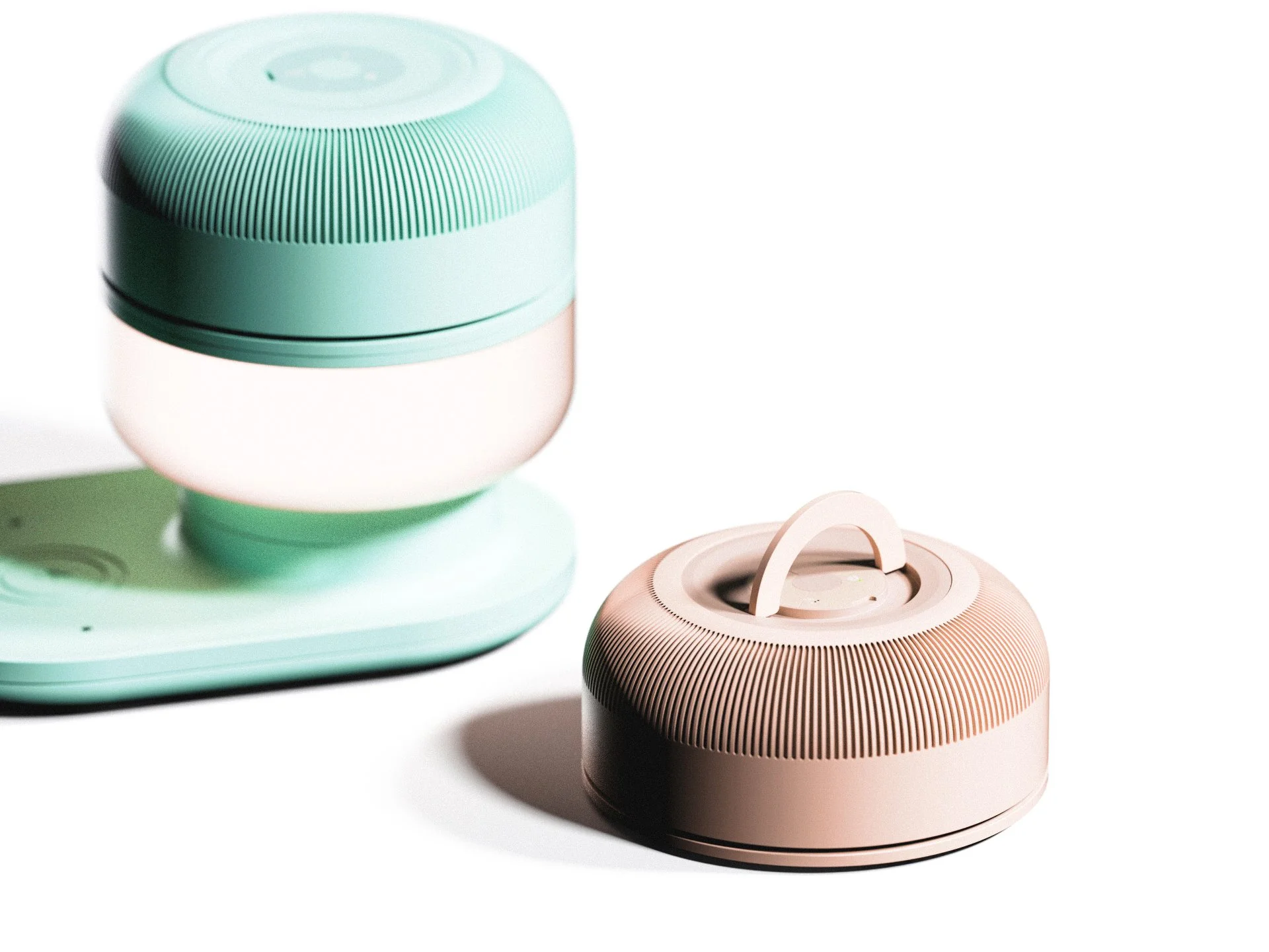 A mint green smart speaker on its charging base and a light pink smart speaker with a handle on top, both with a ribbed design, placed on a white surface.