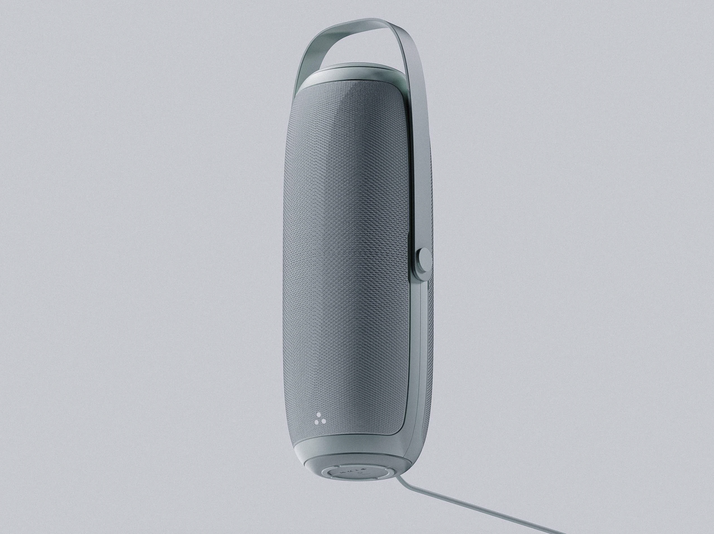 A modern, vertical speaker with a handle at the top, a volume control knob on the side, a speaker grille covering most of its surface, and a charging cable at the bottom, set against a plain, light background.