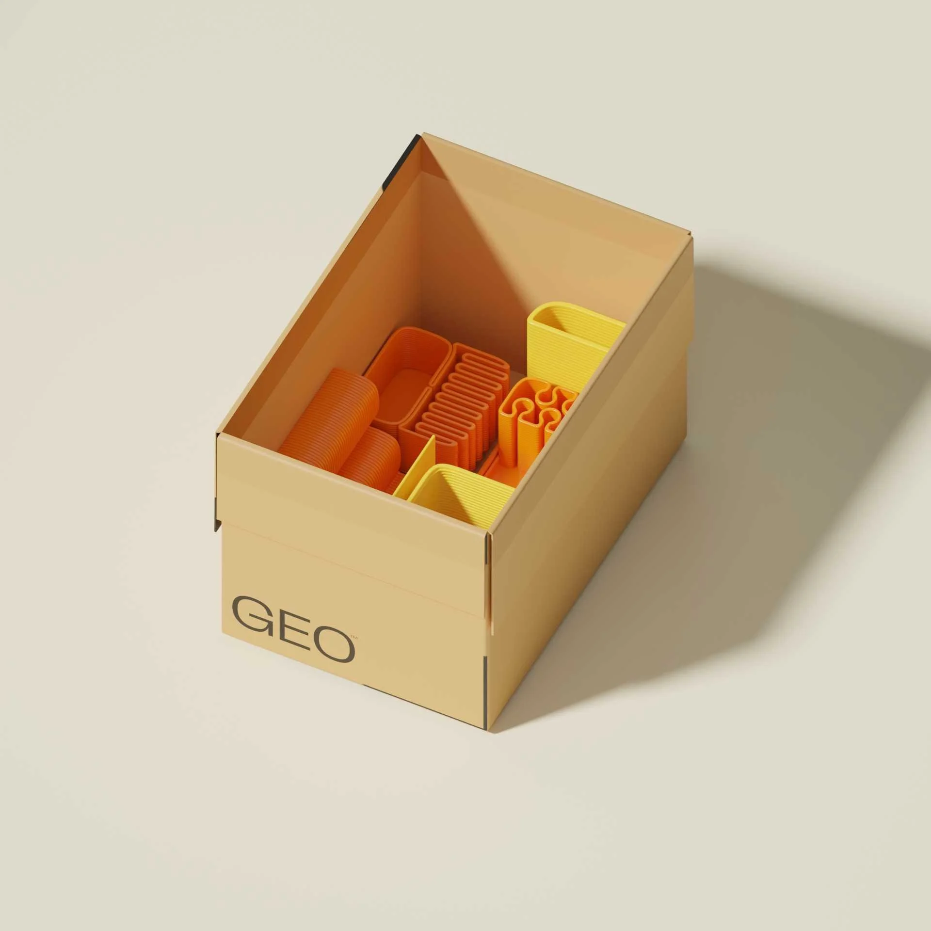Open cardboard box labeled 'GEO' containing various yellow and orange plastic geometric modeling pieces, including rings, cones, and interlocking shapes.