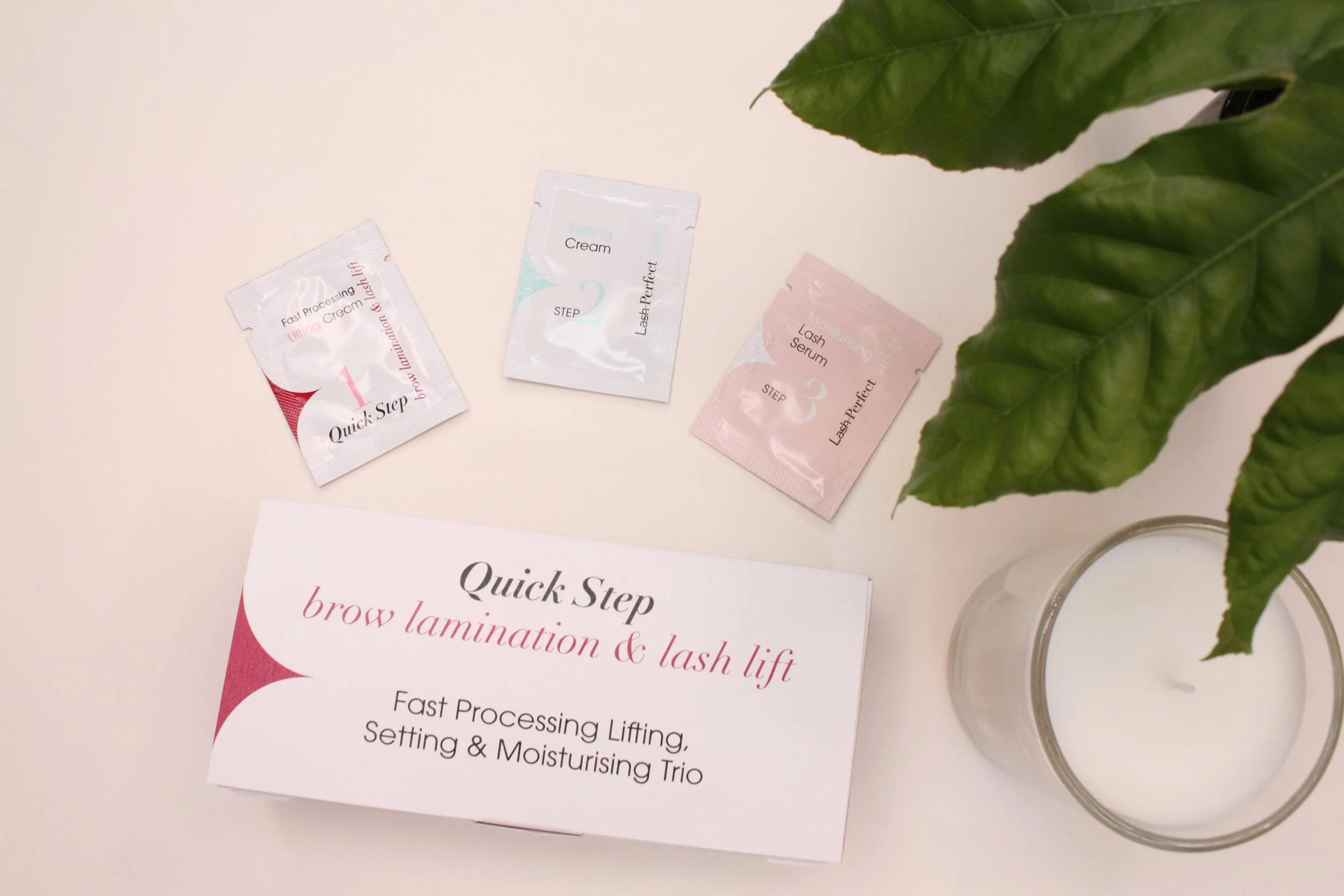 A skincare set with three small packets labeled Quick Step 1, 2, and 3, placed above a white box with pink and black text that reads 'Quick Step brow lamination & lash lift: Fast Processing Lifting, Setting & Moisturising Trio'. The packets are label