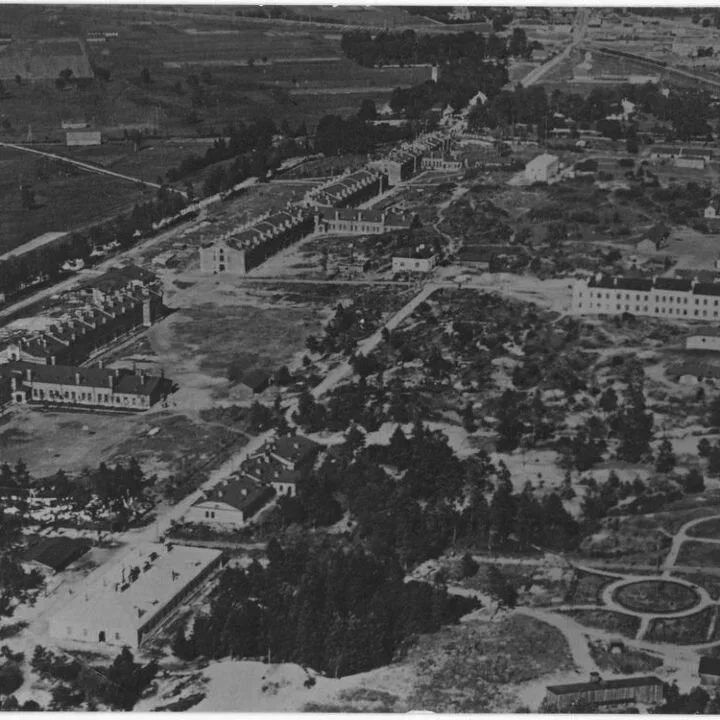 Aerial view of a large historical prison or institutional complex with multiple buildings, surrounded by trees and open land, possibly an old prison or military facility.