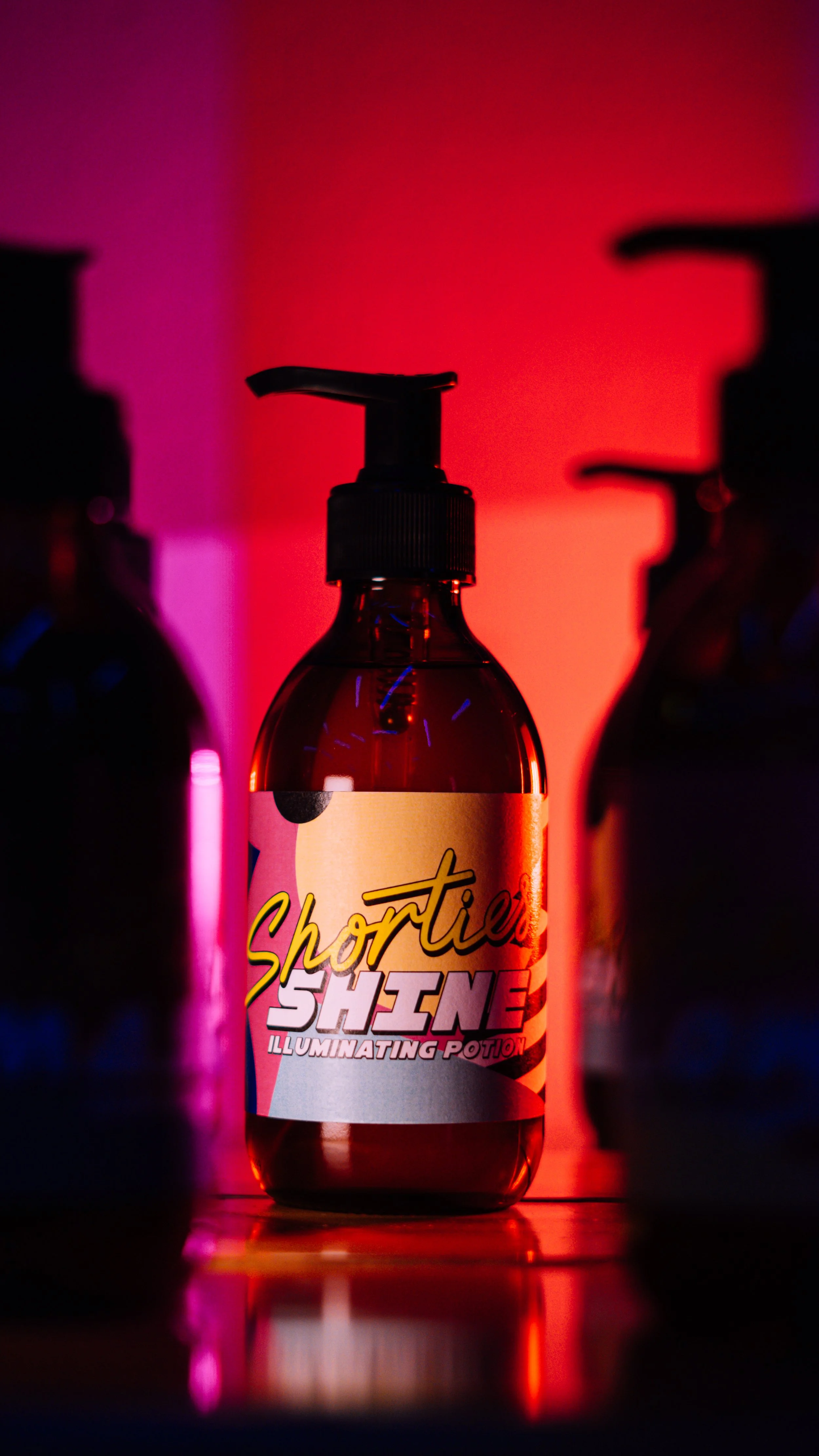 A bottle labeled "Shortie Shine" with a pump top, illuminated by colorful neon lights in pink and red hues, with other bottle silhouettes in the background.