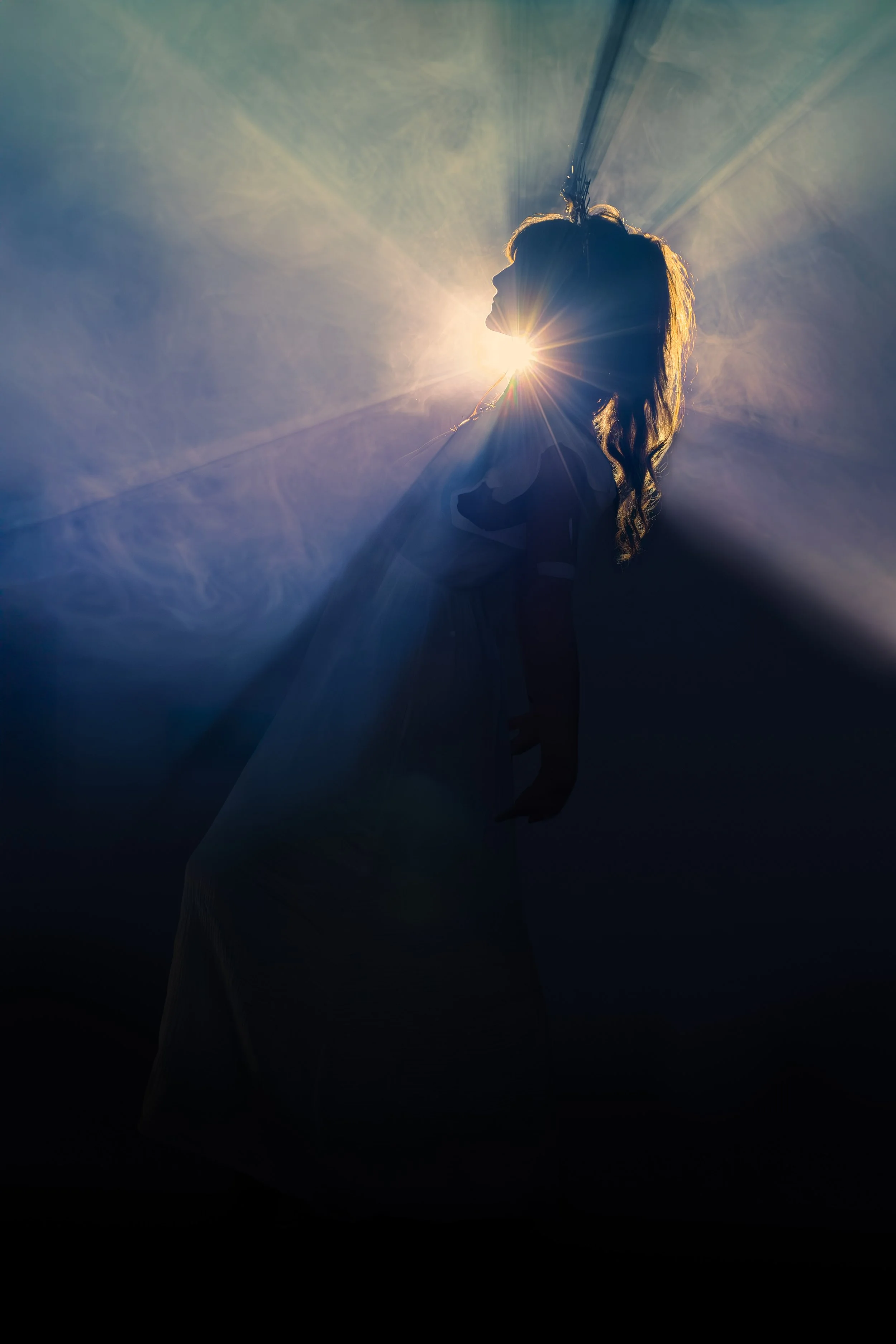 Portrait en contre-jour avec rayons lumineux, ambiance poétique et naturelle en extérieur.