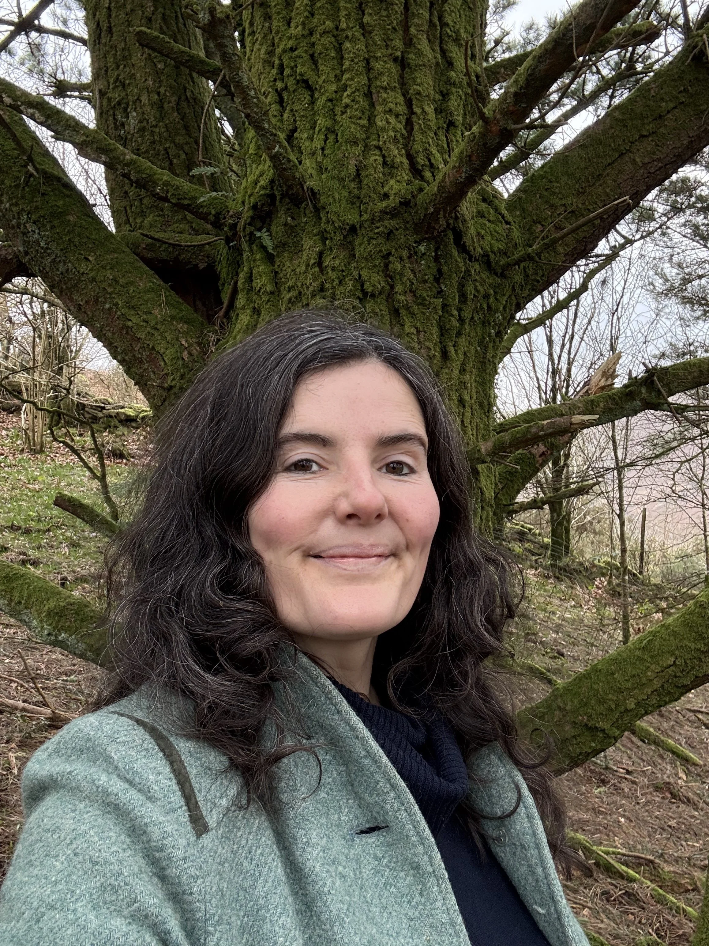 Woman standing by tree smiling
