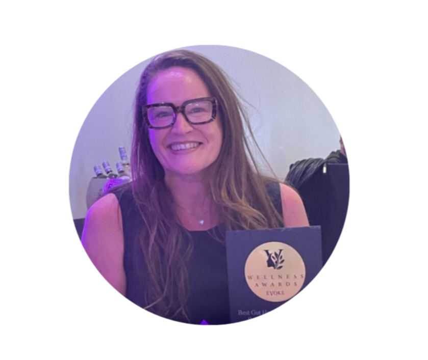 Woman with long hair and glasses smiling, holding a wellness award certificate.