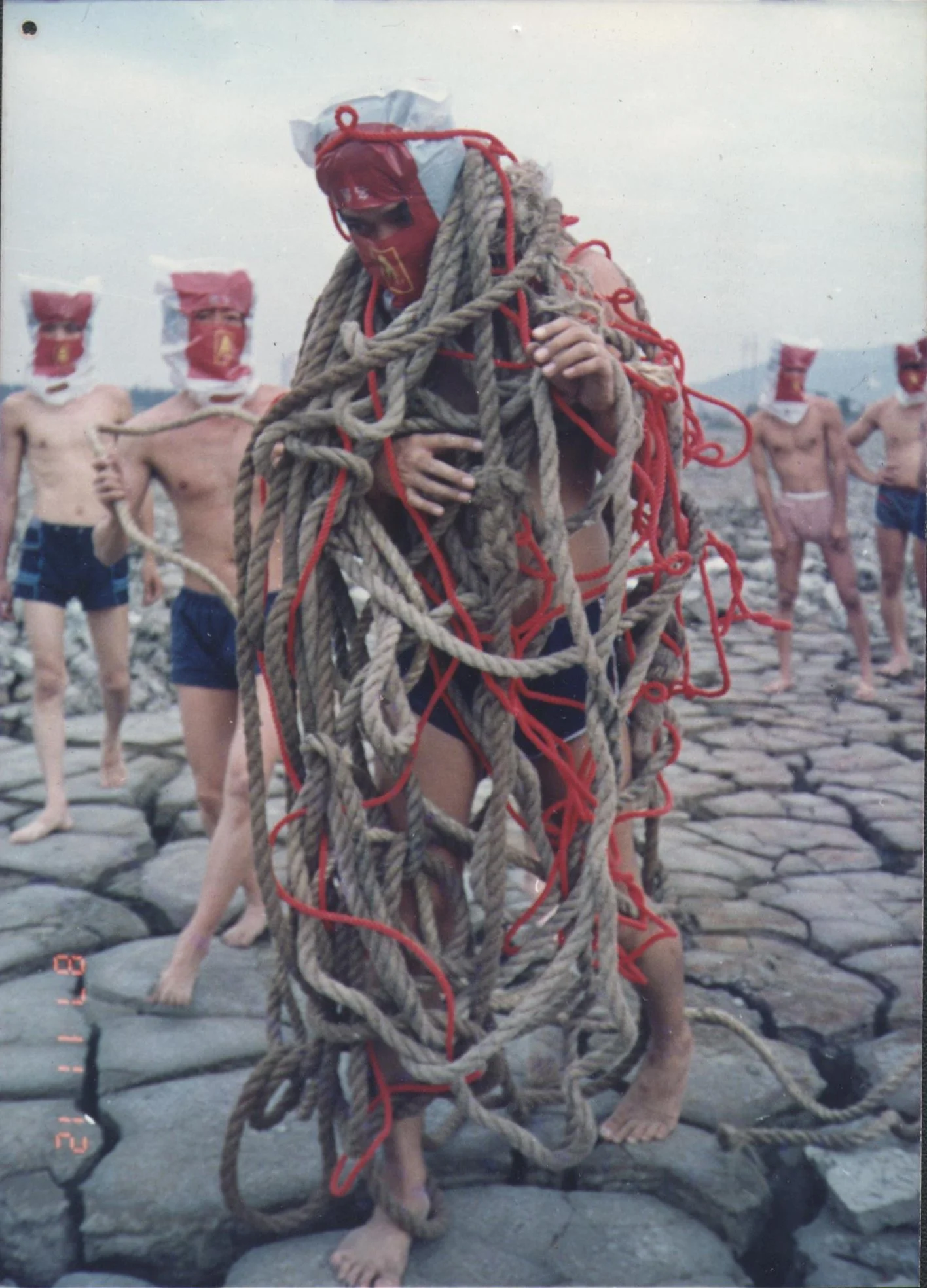 林嘉华和自愿参与者 
Lin Jiahua and volunteer participants
纠缠捆绑艺术行为
Entanglement and Bondage Art Performance 
厦门 筼筜港 枯泥滩   Xaimen 1987 
吴艺明摄影 Photography by Wu Yiming