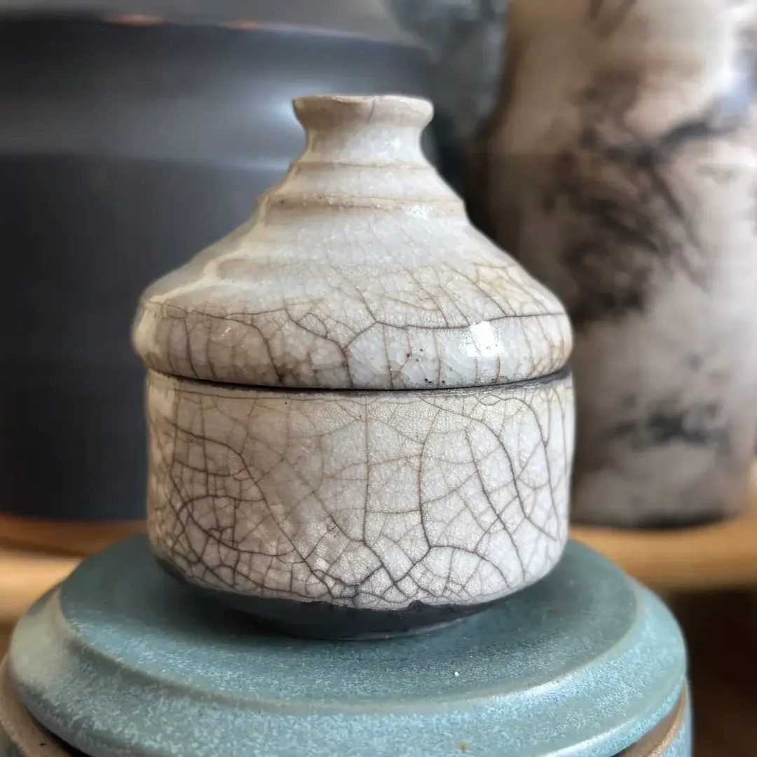 Keramikask i neutral ton med krackelerad glasyr.