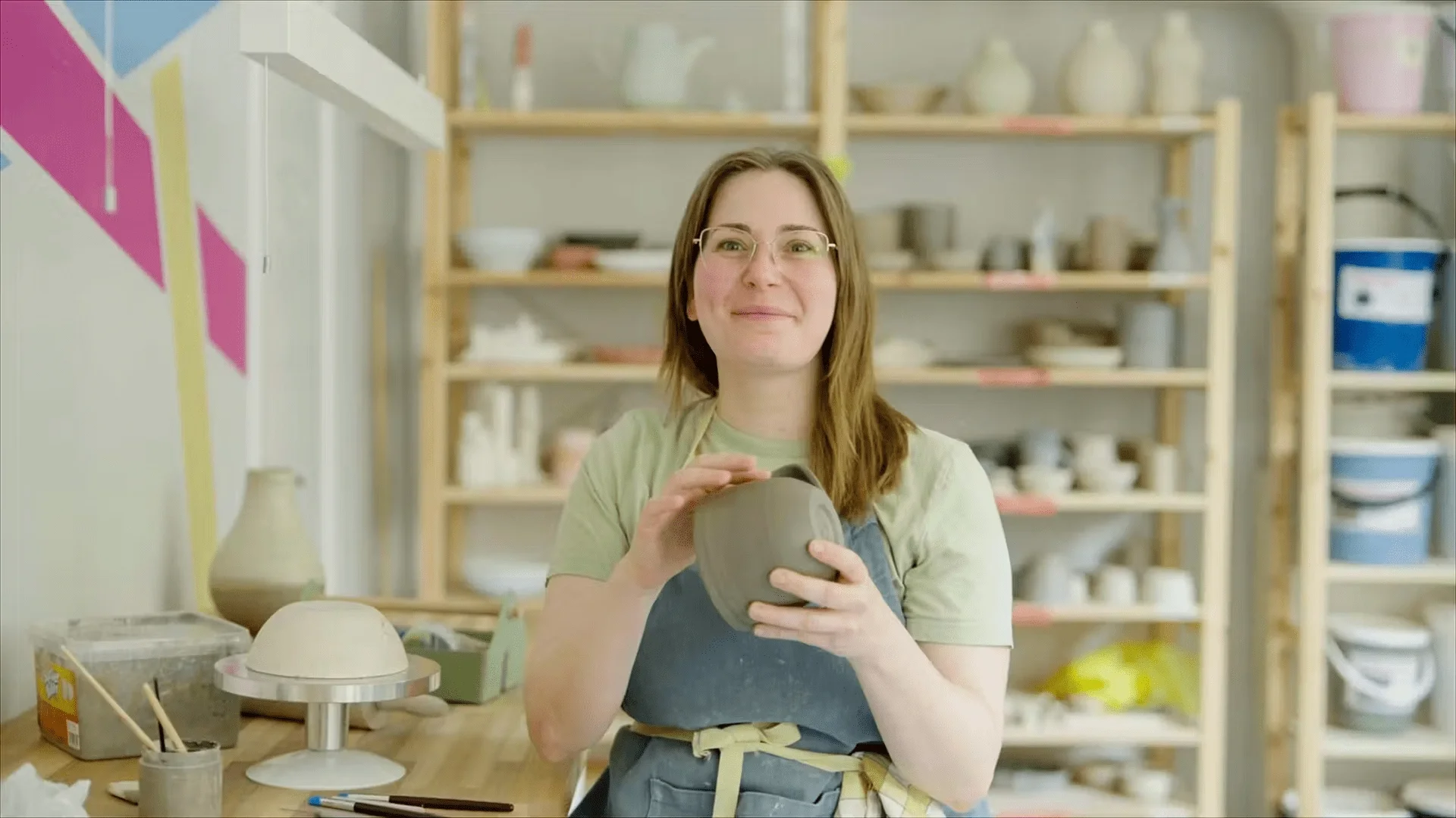 Kvinna som håller en keramikskål i en keramikverkstad.