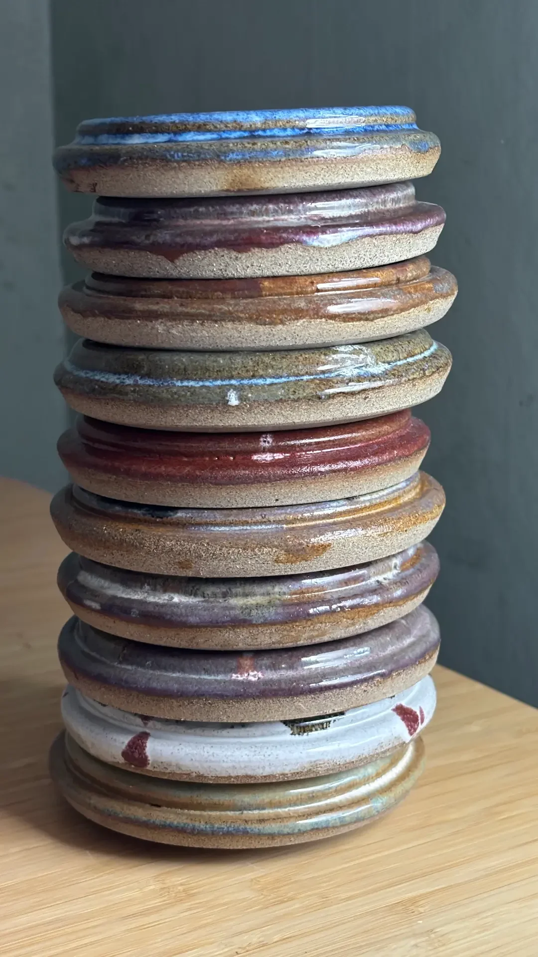 En hög med keramiska fat eller tallrikar staplade på varandra på ett träbord.