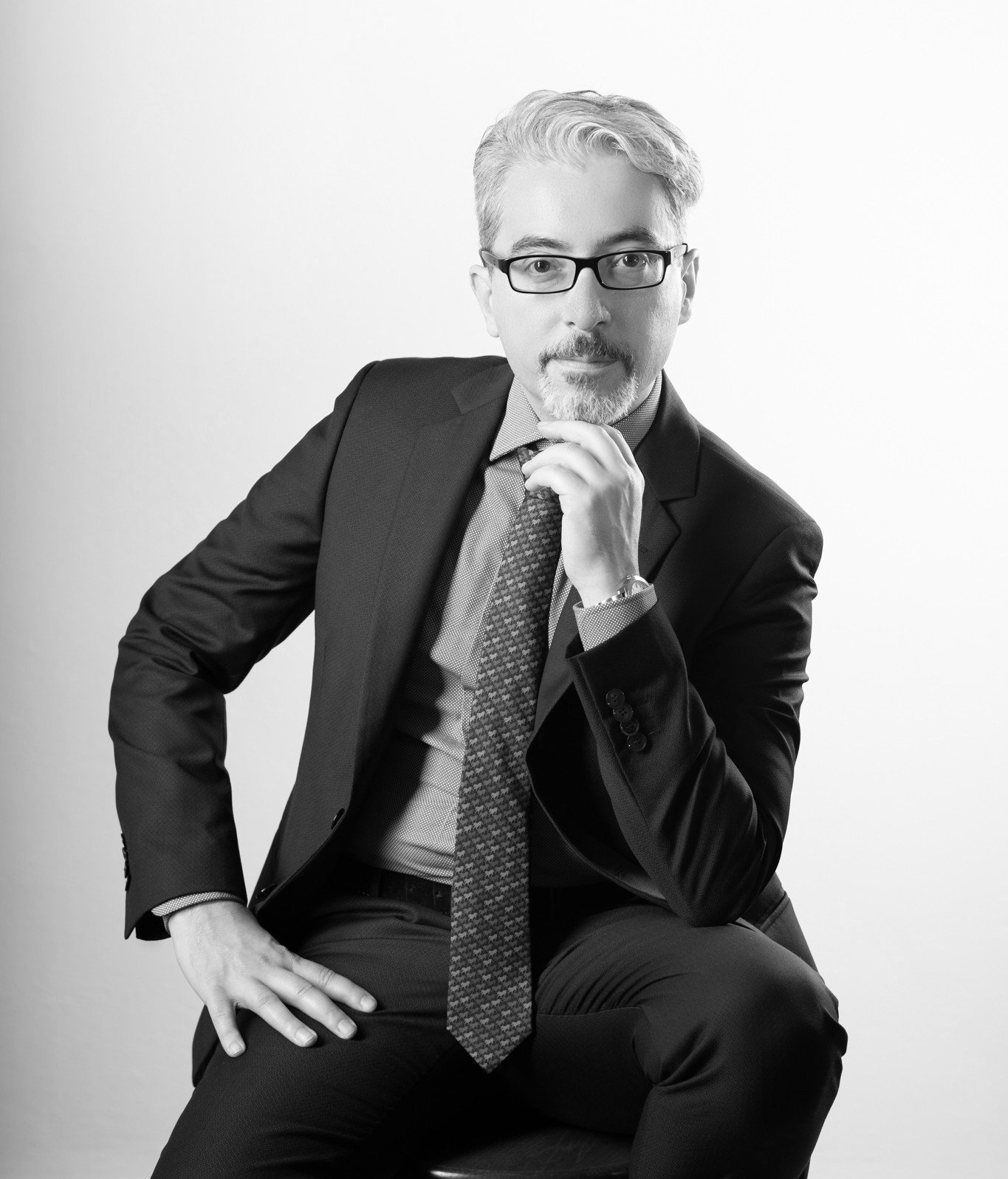 A professional portrait of Global Strategist Simone Dongu, capturing a contemplative thinking pose in a studio setting.