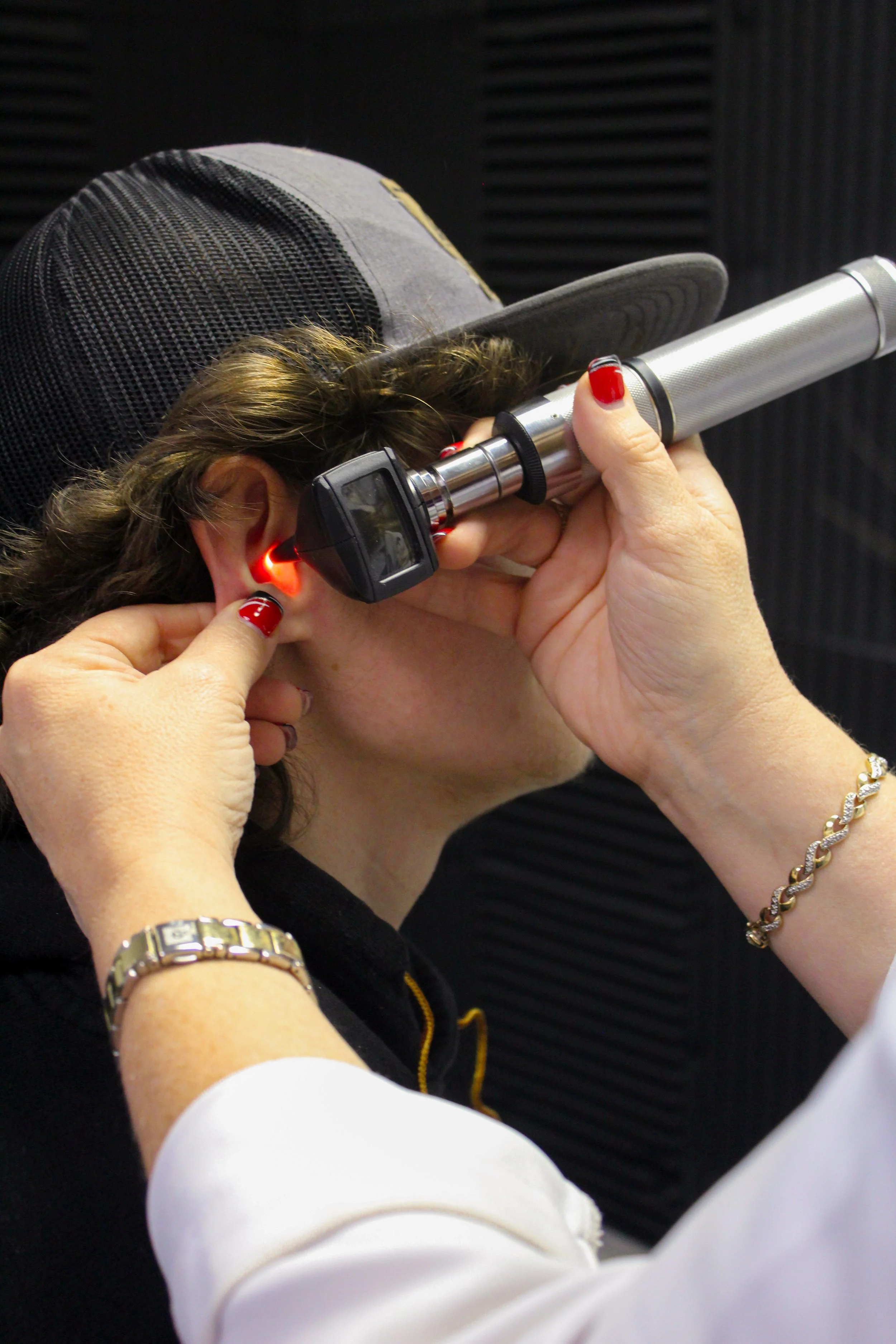 A person undergoing an ear examination with an otoscope, led light on the ear canal.