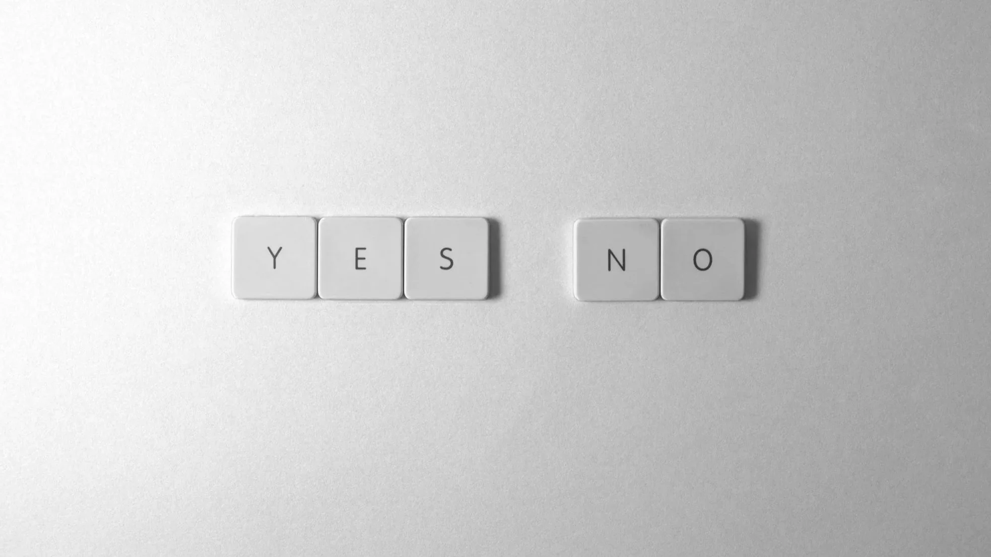 Tuiles de clavier blanc, affichant deux mots côte à côte, 'YES' et 'NO' sur fond gris clair.