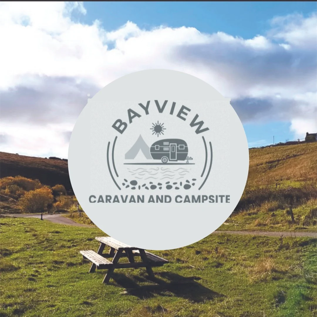 Logo for Bay View Caravan and Campsite overlaying the campsite under a partly cloudy sky.