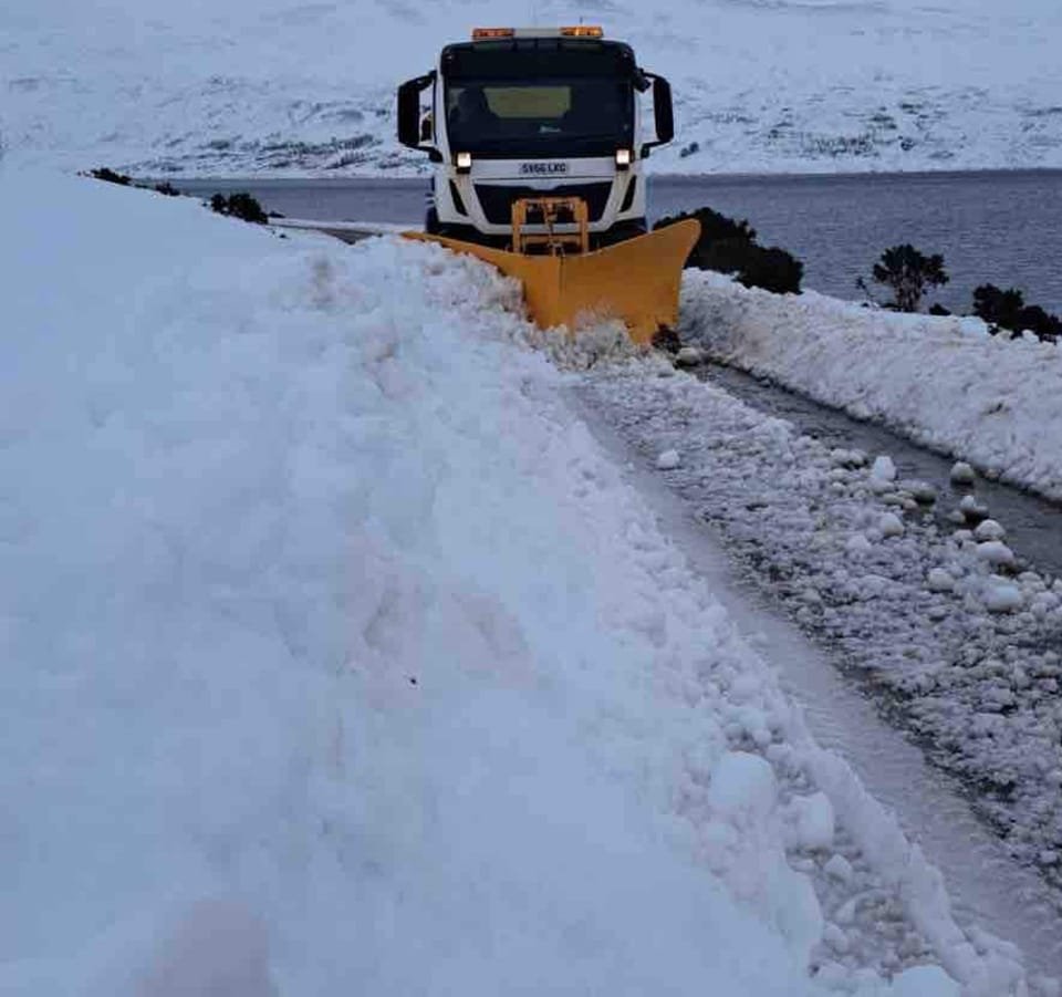 A snow plow clearing snow from the edge of Loch Loyal.