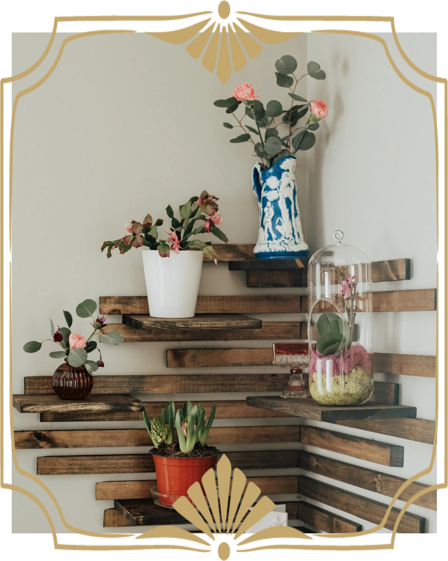 A wooden wall shelf with assorted potted plants and flowers in decorative vases and pots, displayed against a plain wall.
