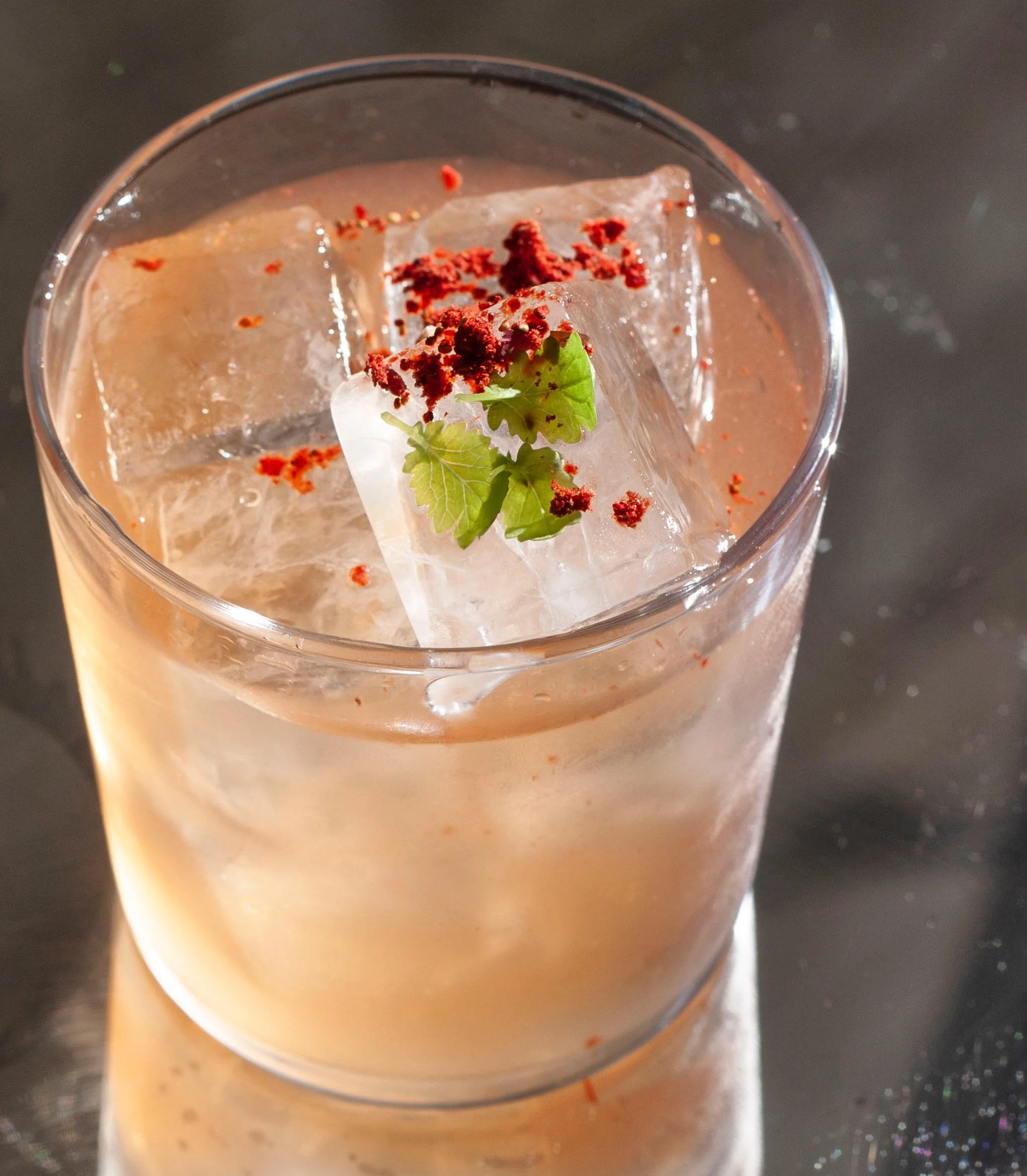 Verre de cocktail avec glaçons, garniture de feuilles de coriandre, poudre rouge