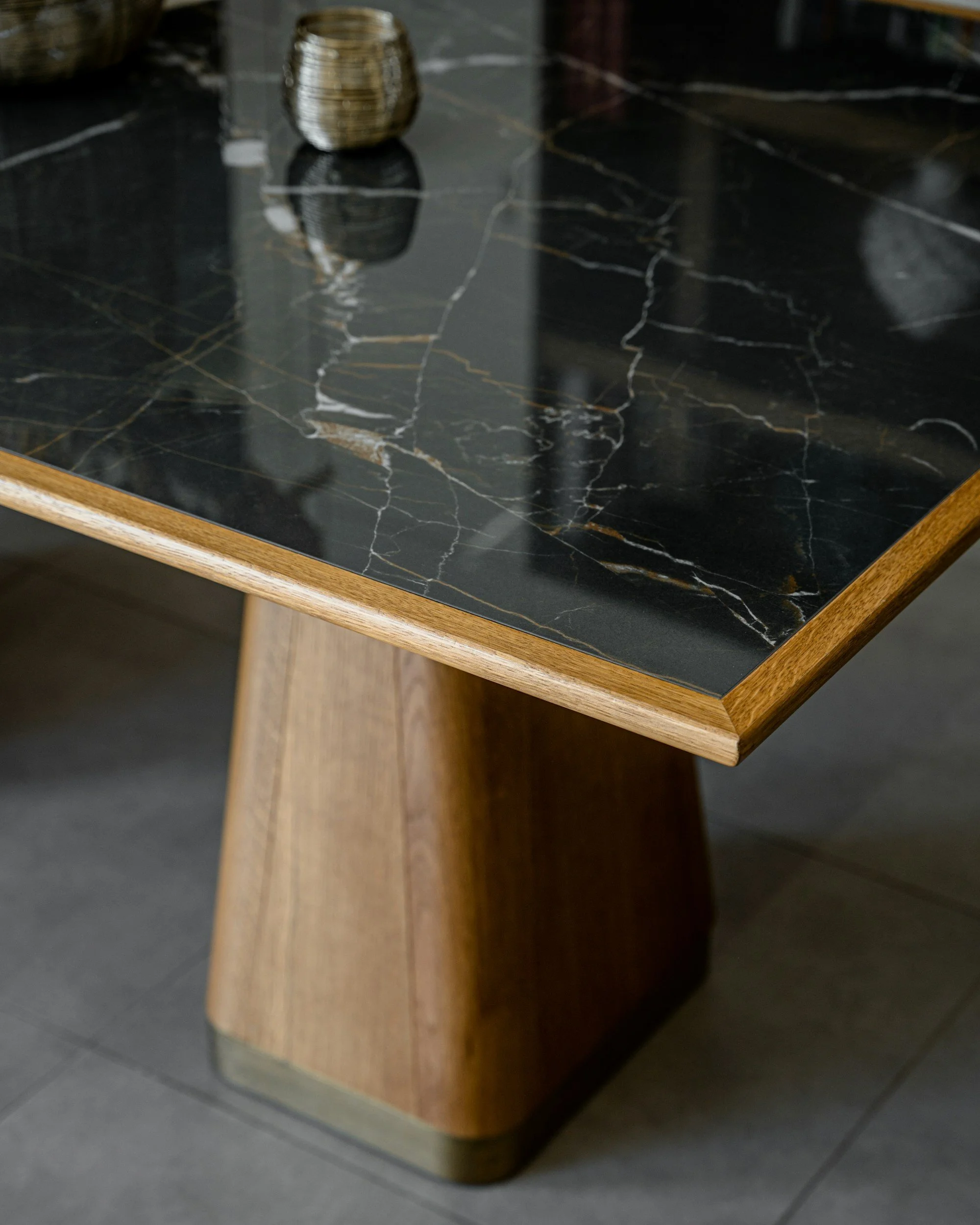 Close-up of a black marble tabletop with gold and white veining, supported by a wooden base.
