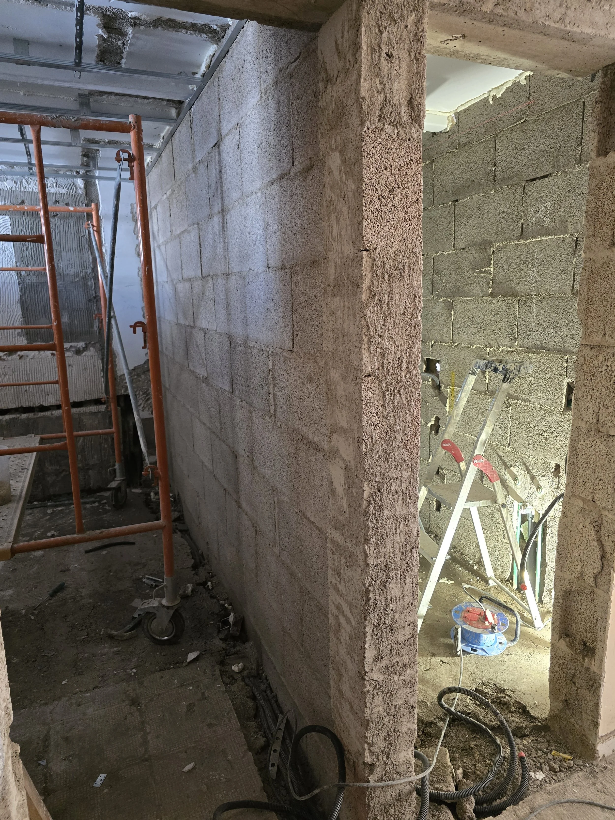 Construction site with brick walls, a stepladder, and scaffolding.