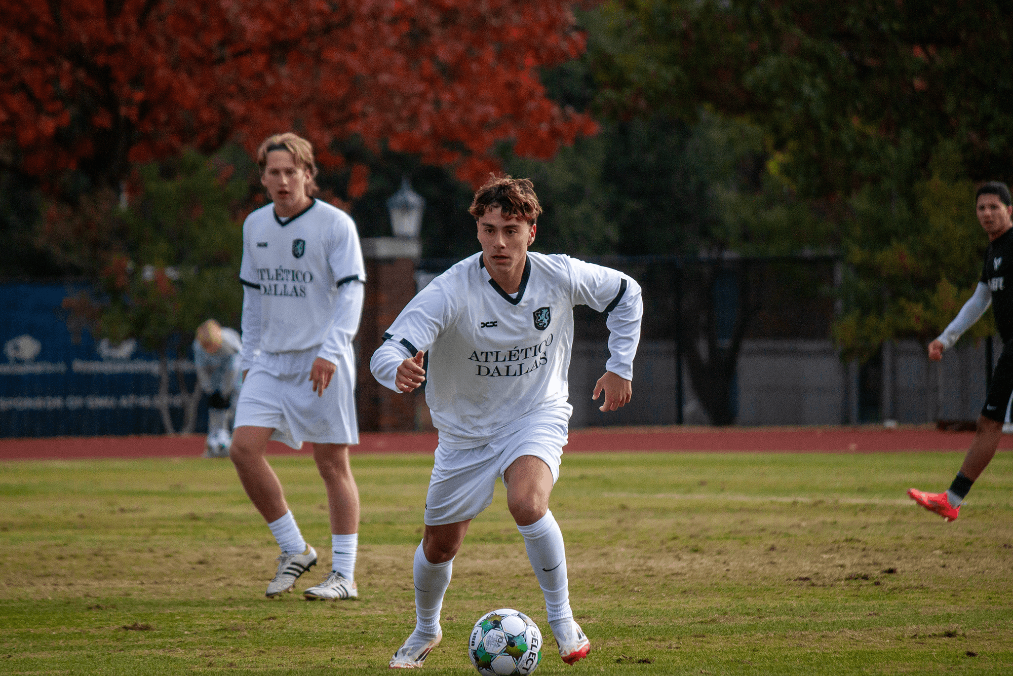 Two men playing soccer on a grassy field