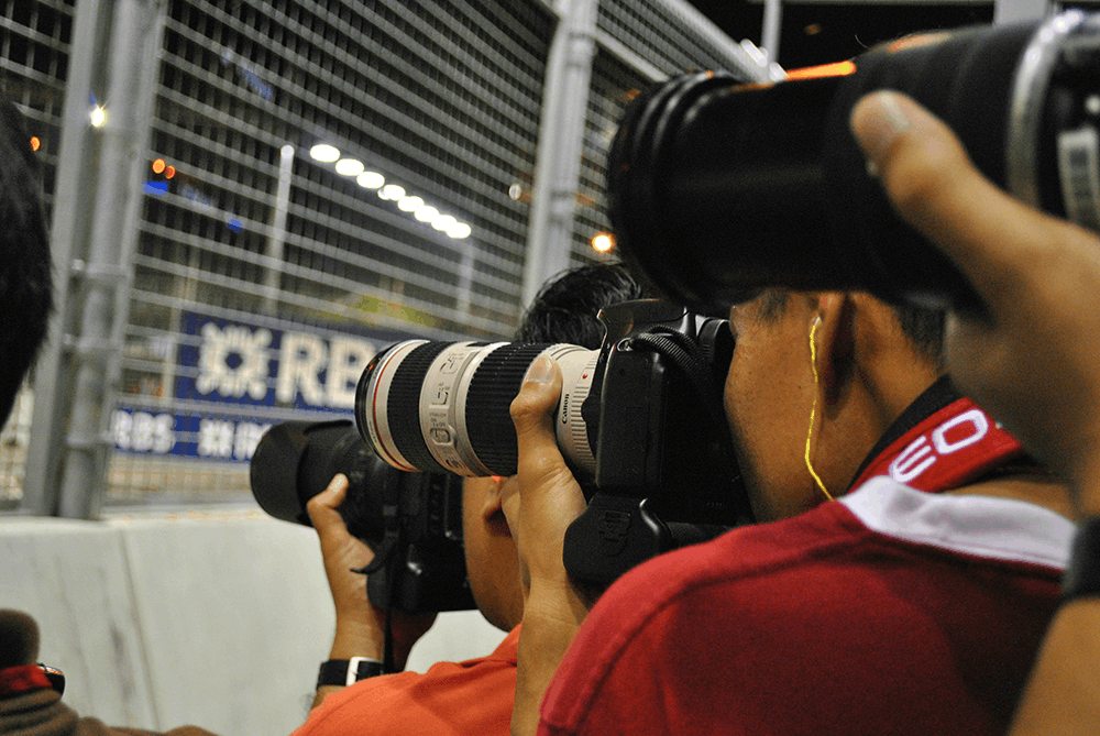 People taking photos with camera at a sports stadium.
