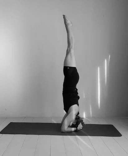 Vrouw die een hoofstand uitvoert op een mat in een kamer