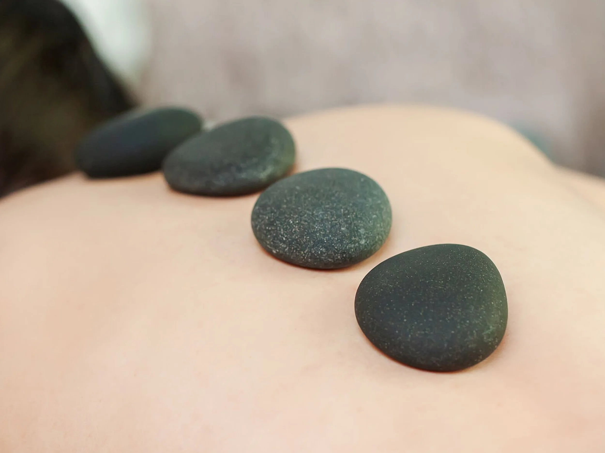 Heated volcanic stones arranged along a client's spine to relieve deep muscle tension and promote spinal alignment.