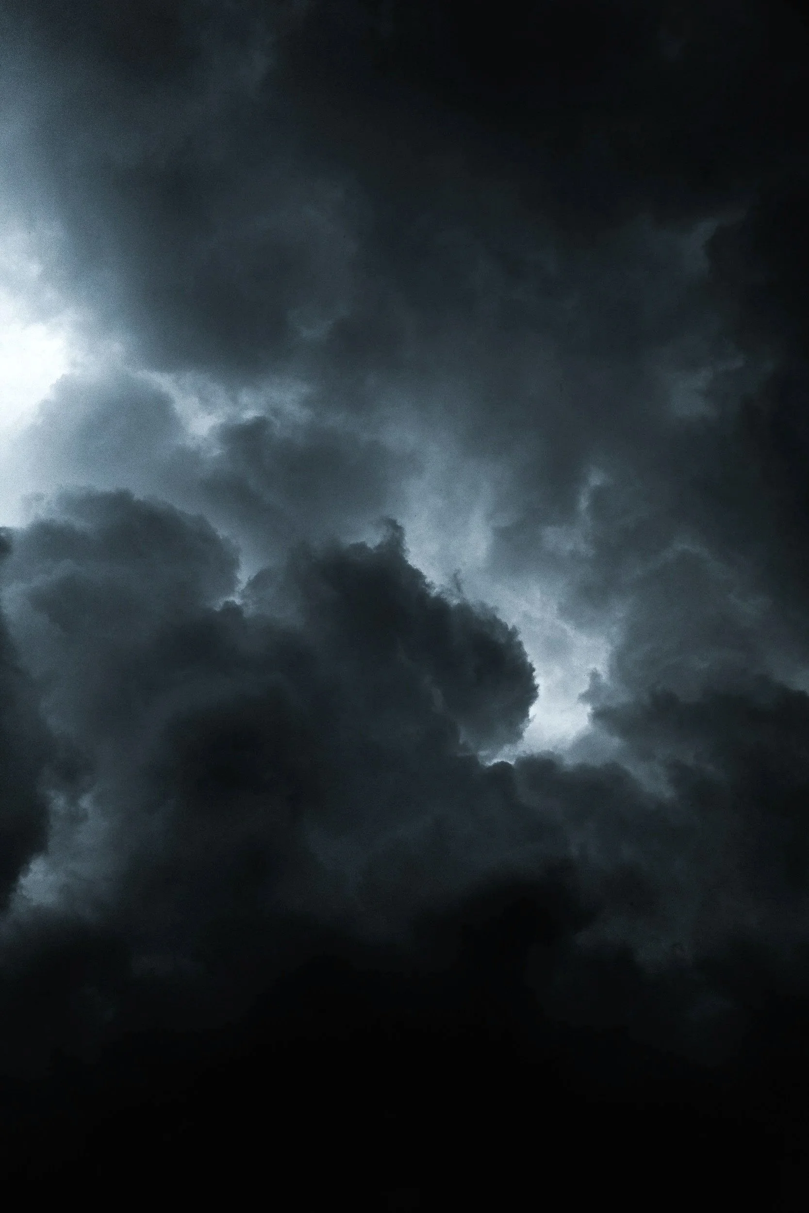 Dark, stormy clouds in the sky with light breaking through.