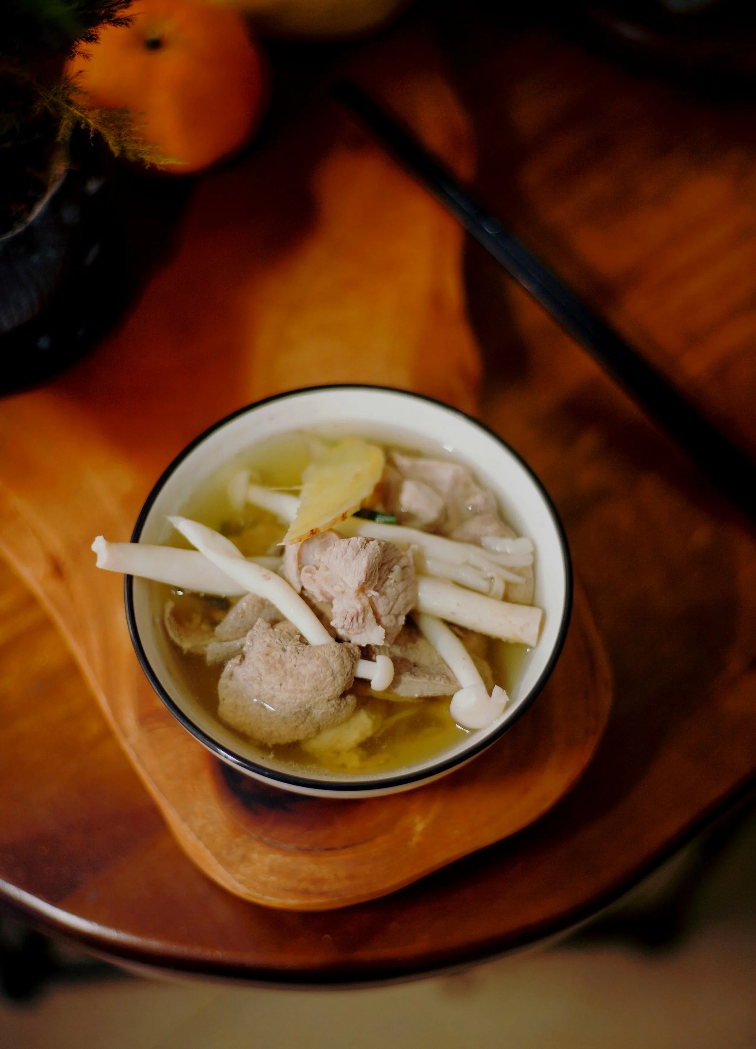 A cup of chicken and mushroom soup on a wooden tray.