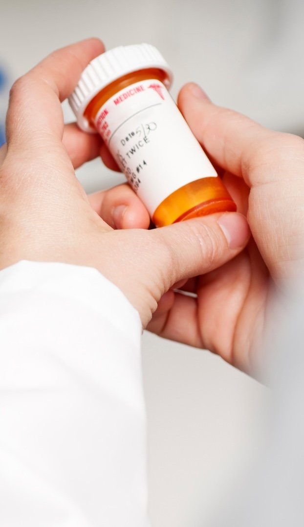 A pair of hands holding a prescription pill bottle