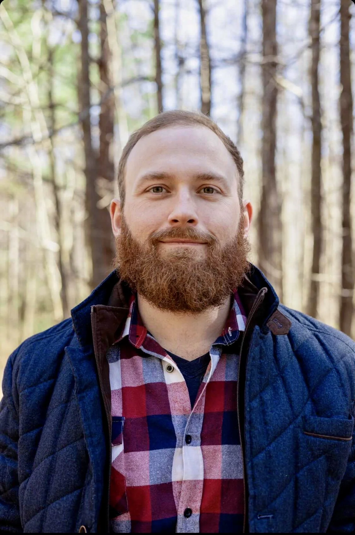 owner, well dressed man with beard standing outside, smiles and looks into camera