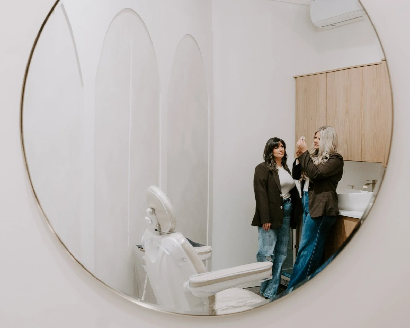 Two women prepping for a medical aesthetic client in a clean med spa clinic room.