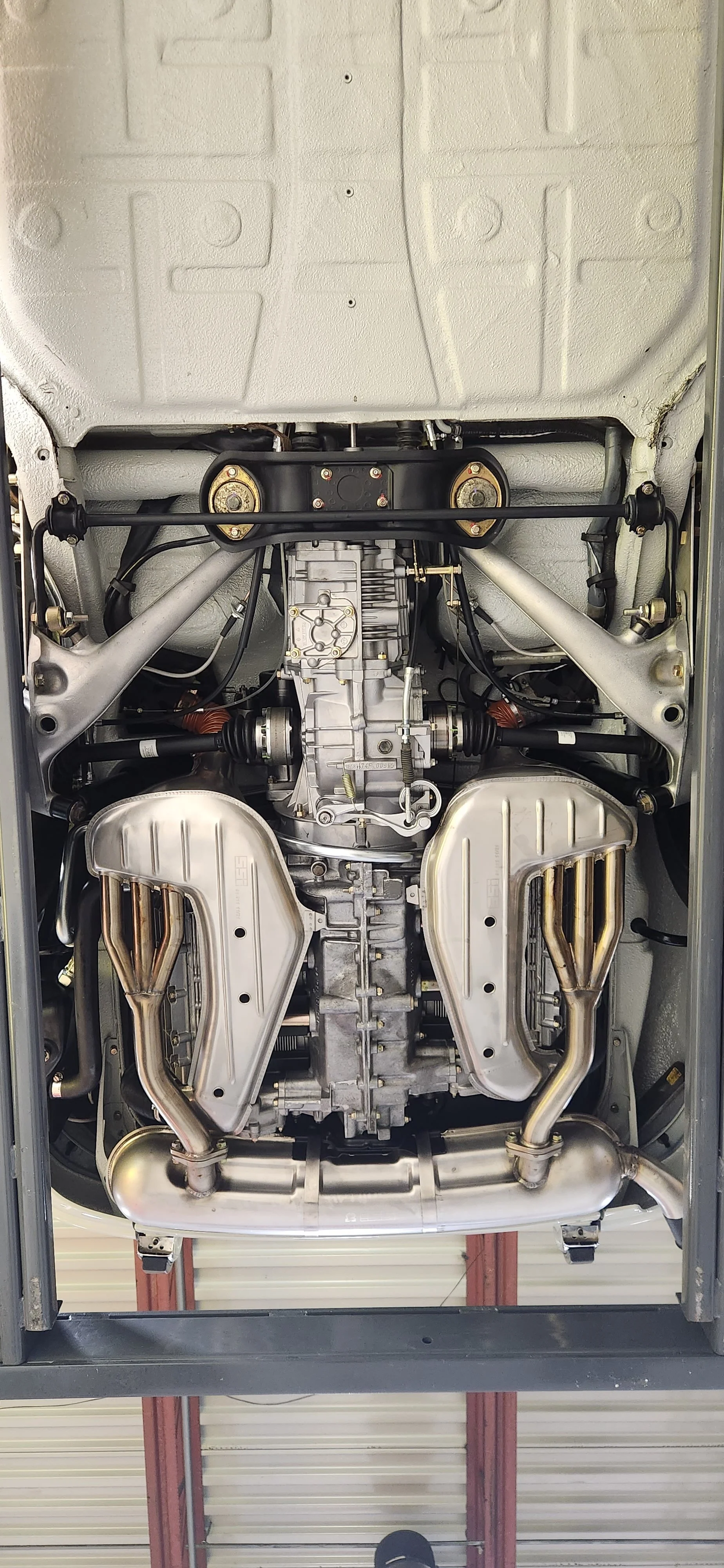 Underbody view of a car's engine with exhaust headers and other mechanical components.