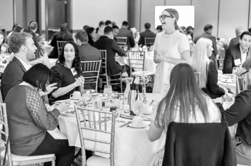 Graduate students sitting around a table sharing a meal and learning about business etiquette and personal development