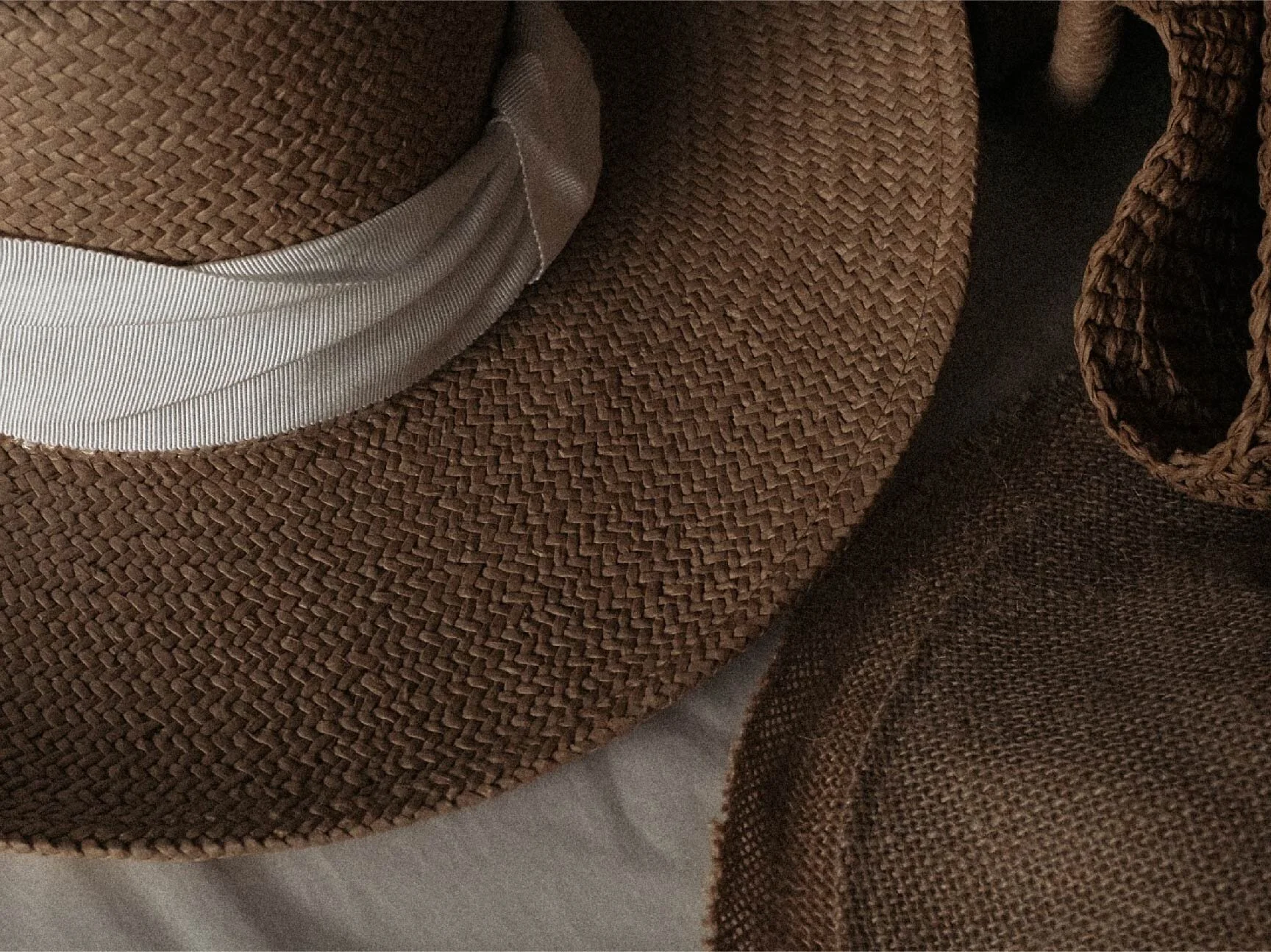 Close-up of two brown woven fabric hats with different textures, one with a light-colored silk or satin trim.