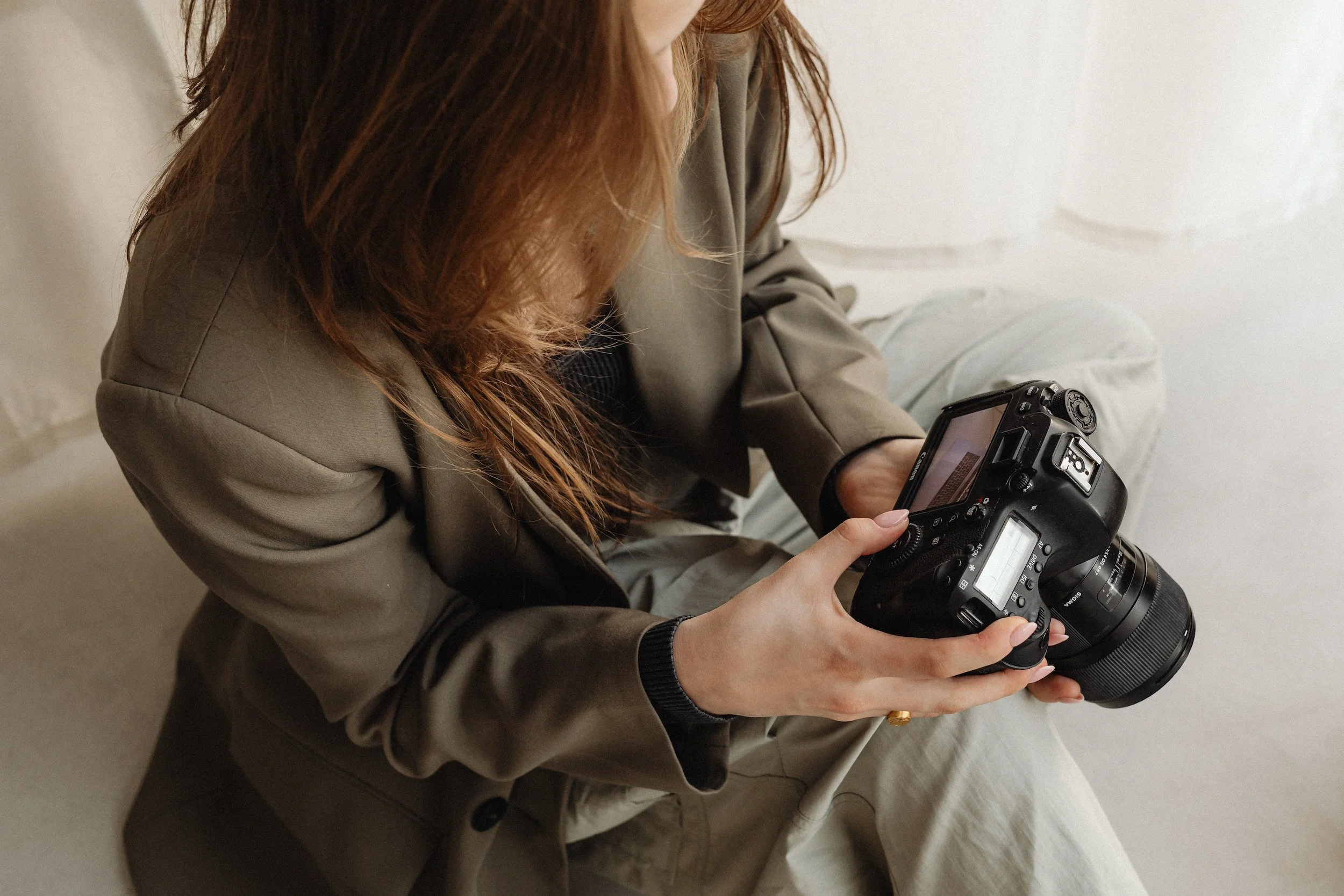 Person with long hair examining a professional camera indoors.