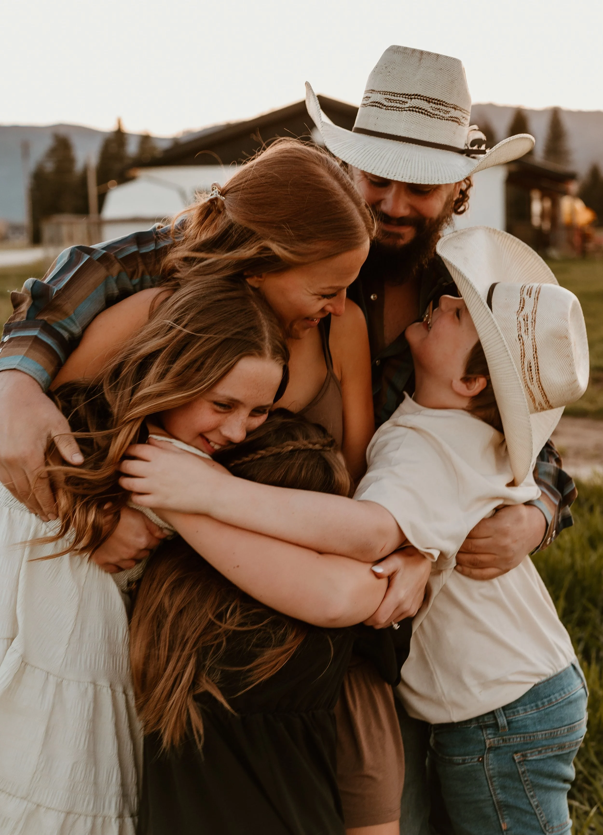 A group of six people hugging outdoors during sunset, smiling and showing affection.