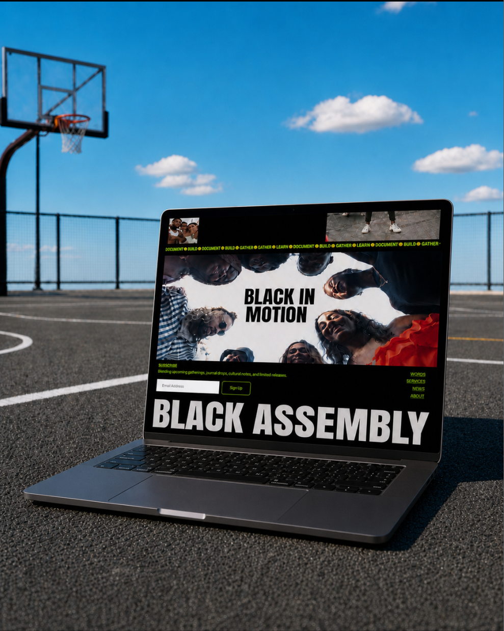 A laptop on an outdoor basketball court displays a webpage promoting an event called 'Black in Motion' and 'Black Assembly' featuring a group of diverse people, with the court, net, and a blue sky with clouds in the background.