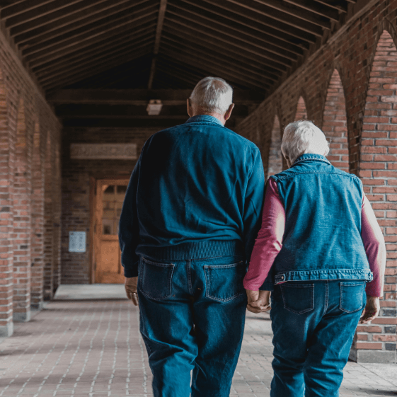An image of an elderly couple holding hands