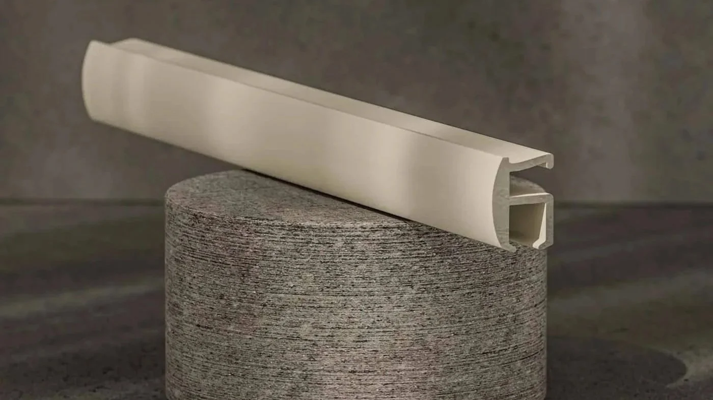 A piece of beige plastic molding resting on a textured cylindrical stone block.