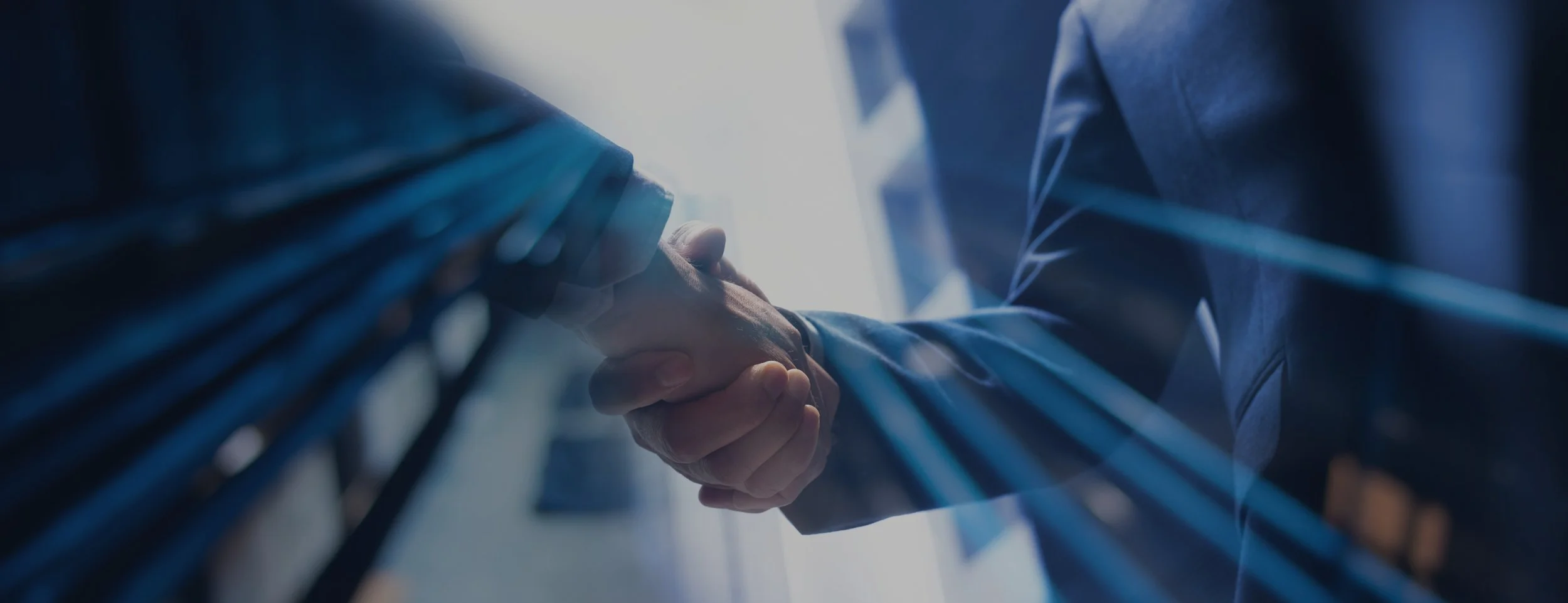 Close-up of two people in business suits shaking hands.