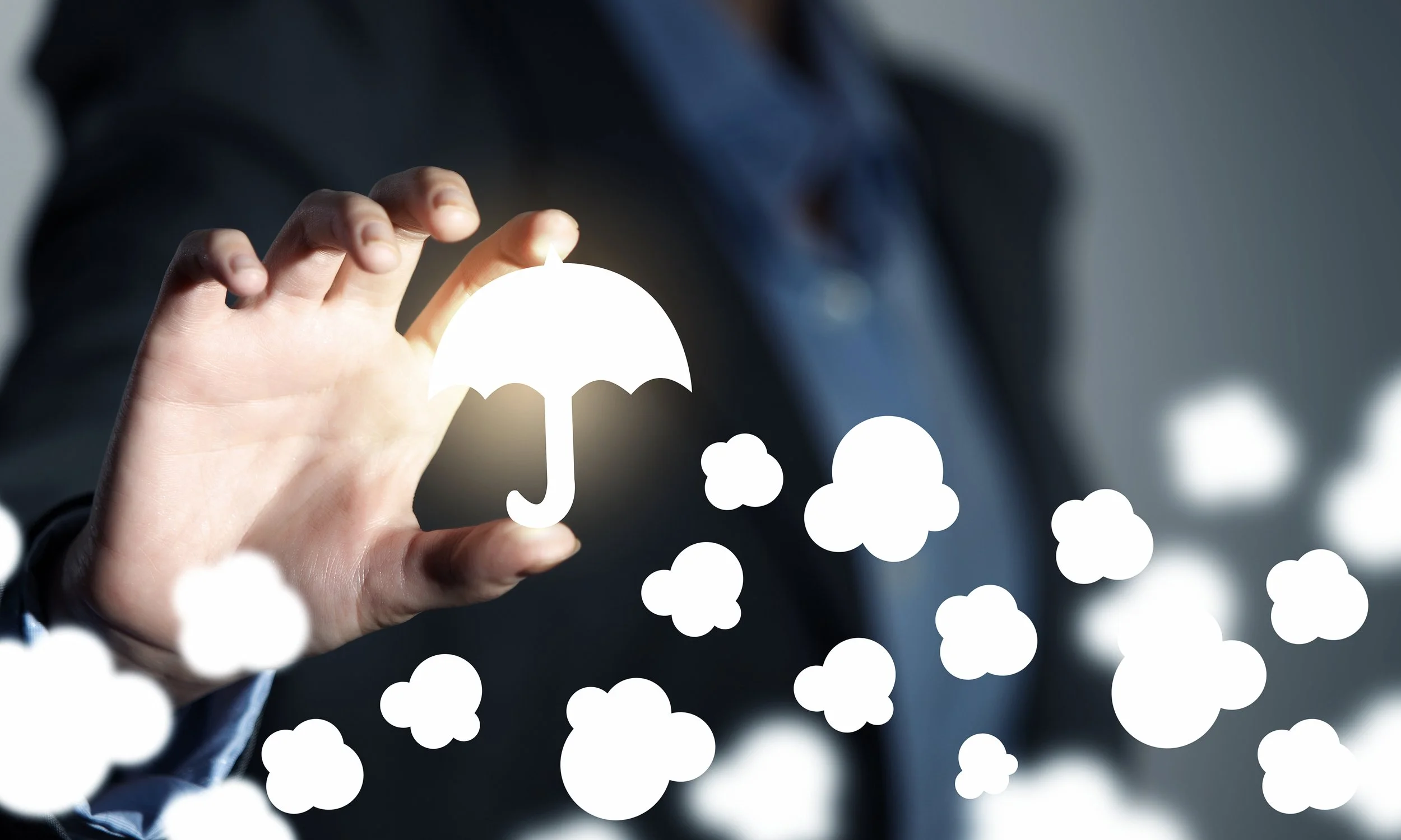 A person in a dark suit holding a glowing umbrella icon with clouds floating around.