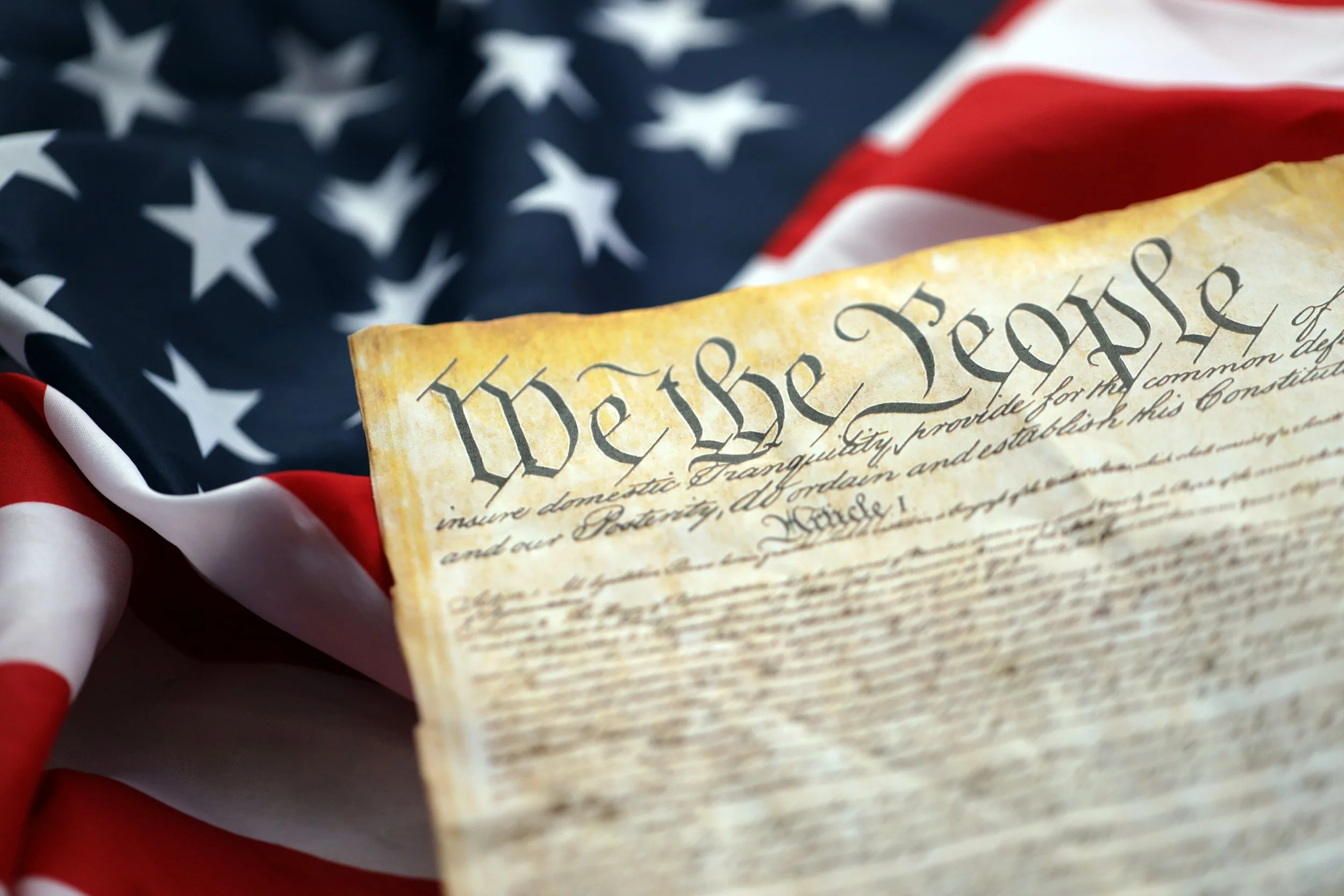 Close-up of the United States Constitution positioned on a folded American flag, symbolizing patriotism and national pride.
