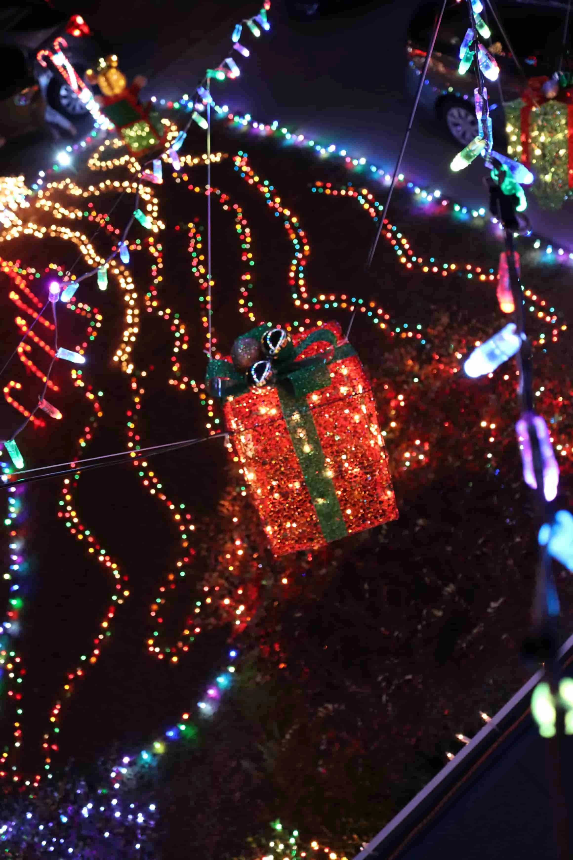 A Christmas display with colorful string lights, a hanging red gift box, and holiday decorations.