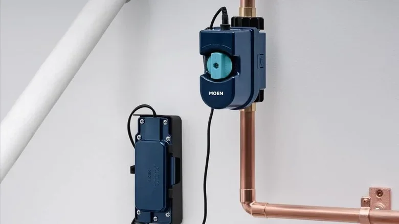 Close-up of a blue electrical switch and an upcoming copper pipe on a white wall.