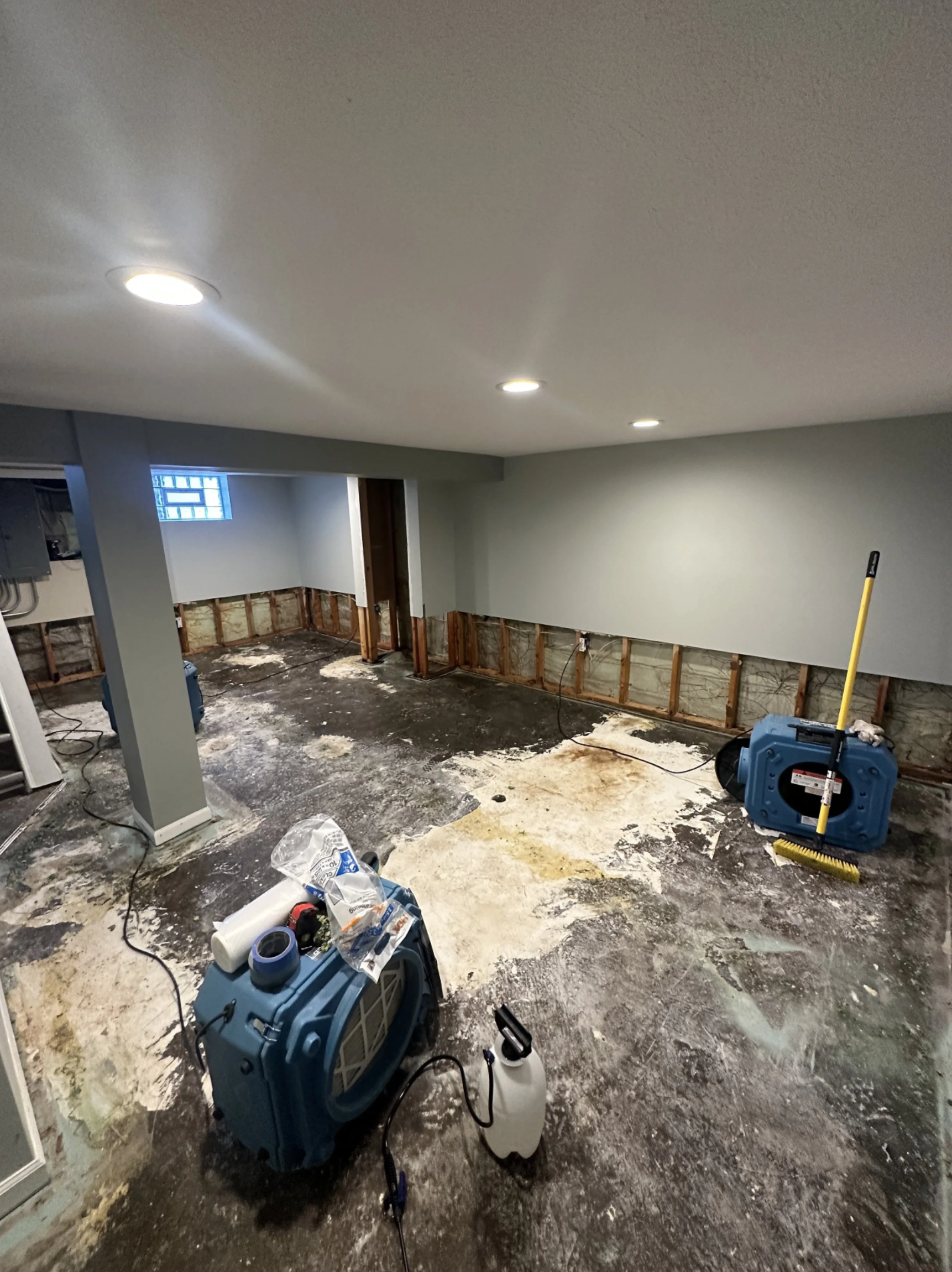 Basement renovation in progress with exposed drywall, construction tools, and equipment on the floor.