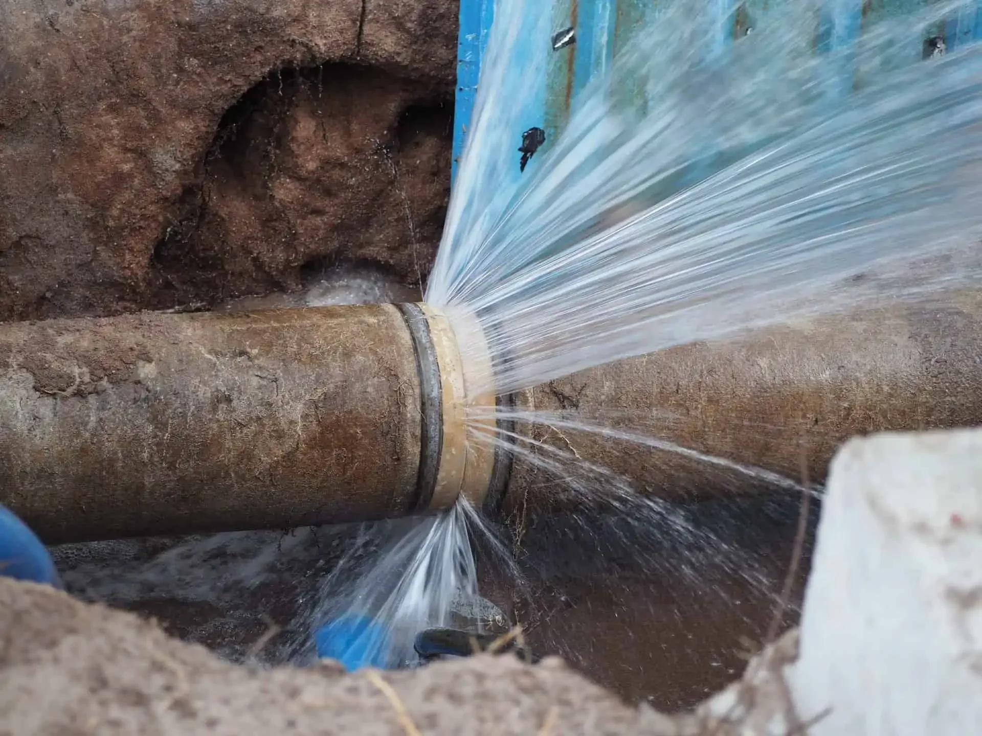 Water is flowing from a large pipe into an underground drainage system.