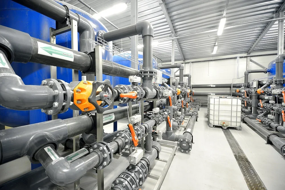 Industrial pipes and valves in a mechanical room or factory setting.