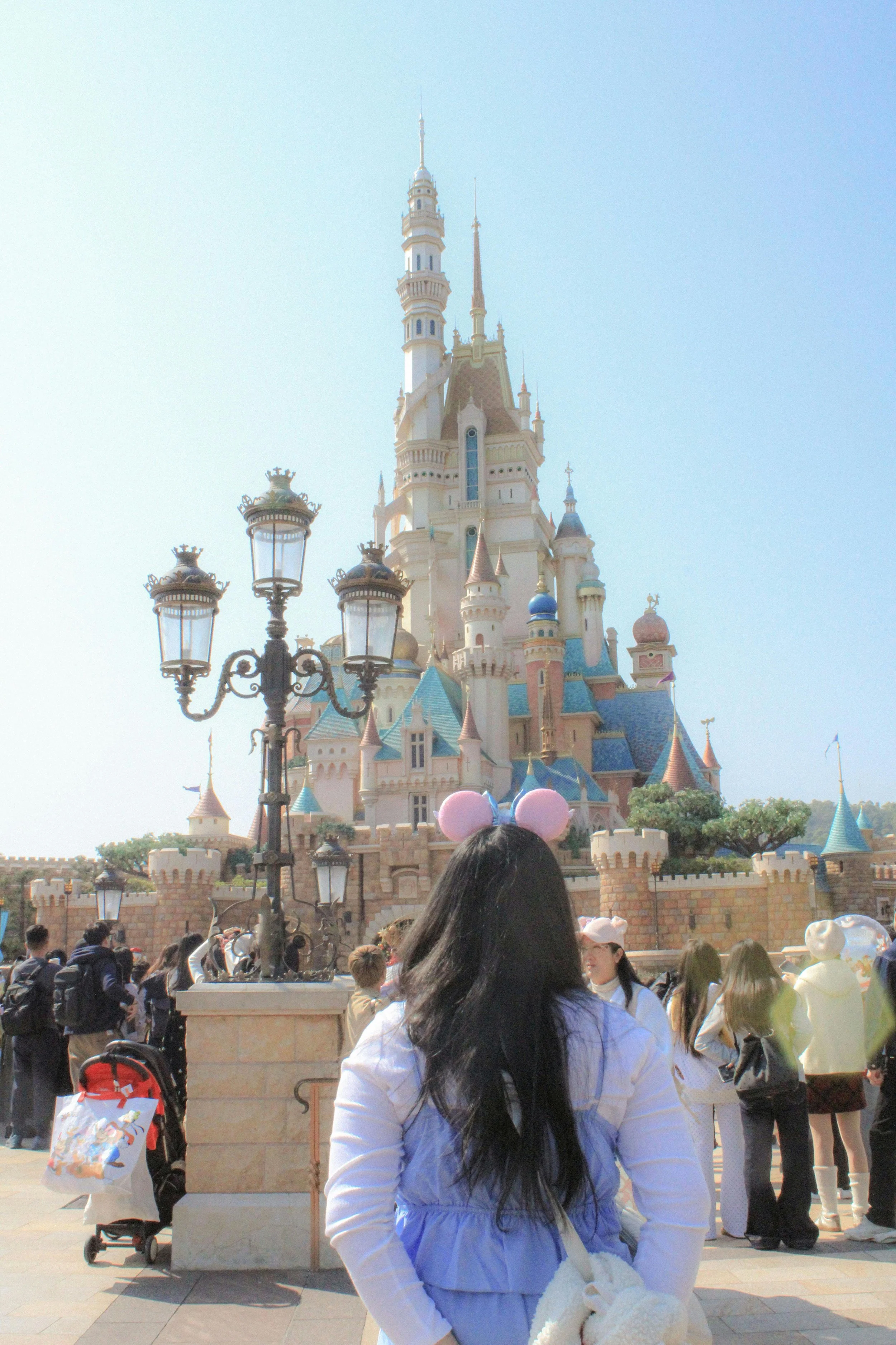 People visiting Disneyland, with Sleeping Beauty Castle in the background, during daytime.