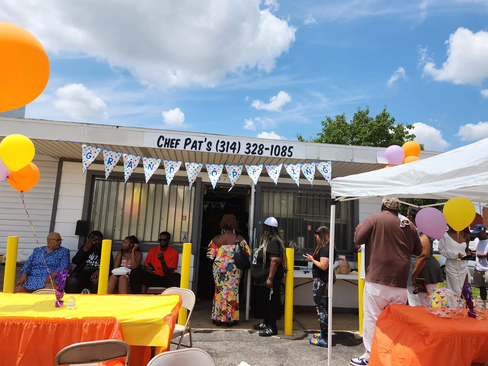 Outdoor grand opening celebration in front of Chef Pat's, with people gathered, balloons, and decorative banners.